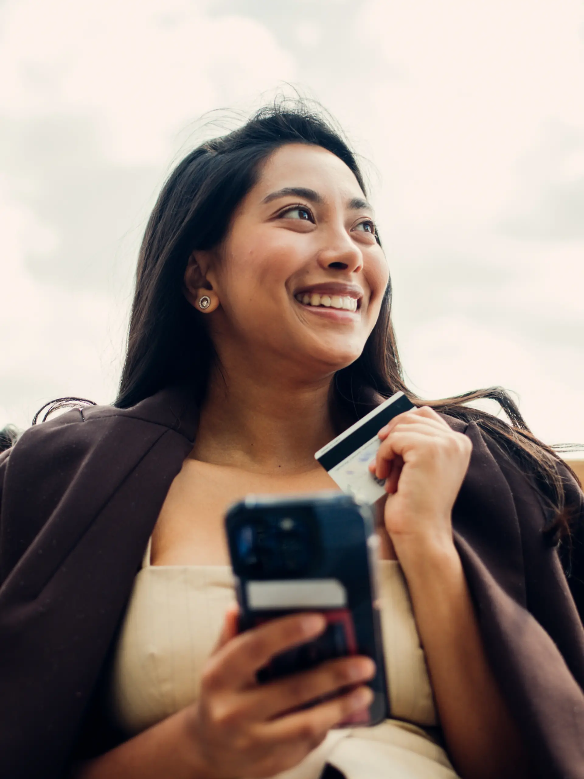 Eine Frau shoppt online mit Kreditkarte und Smartphone.