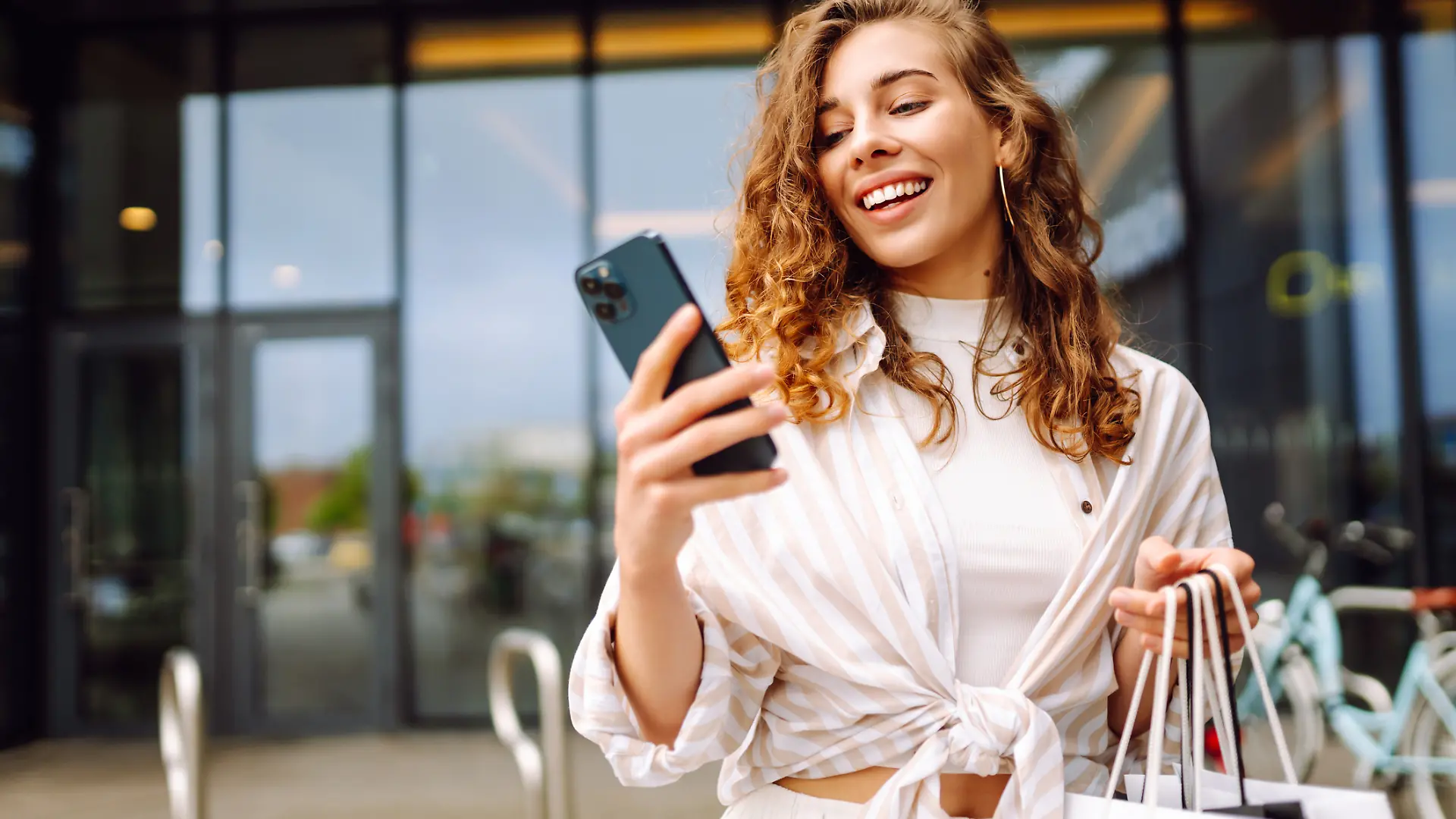 Eine Frau geht shoppen mit Smartphone in der Hand.