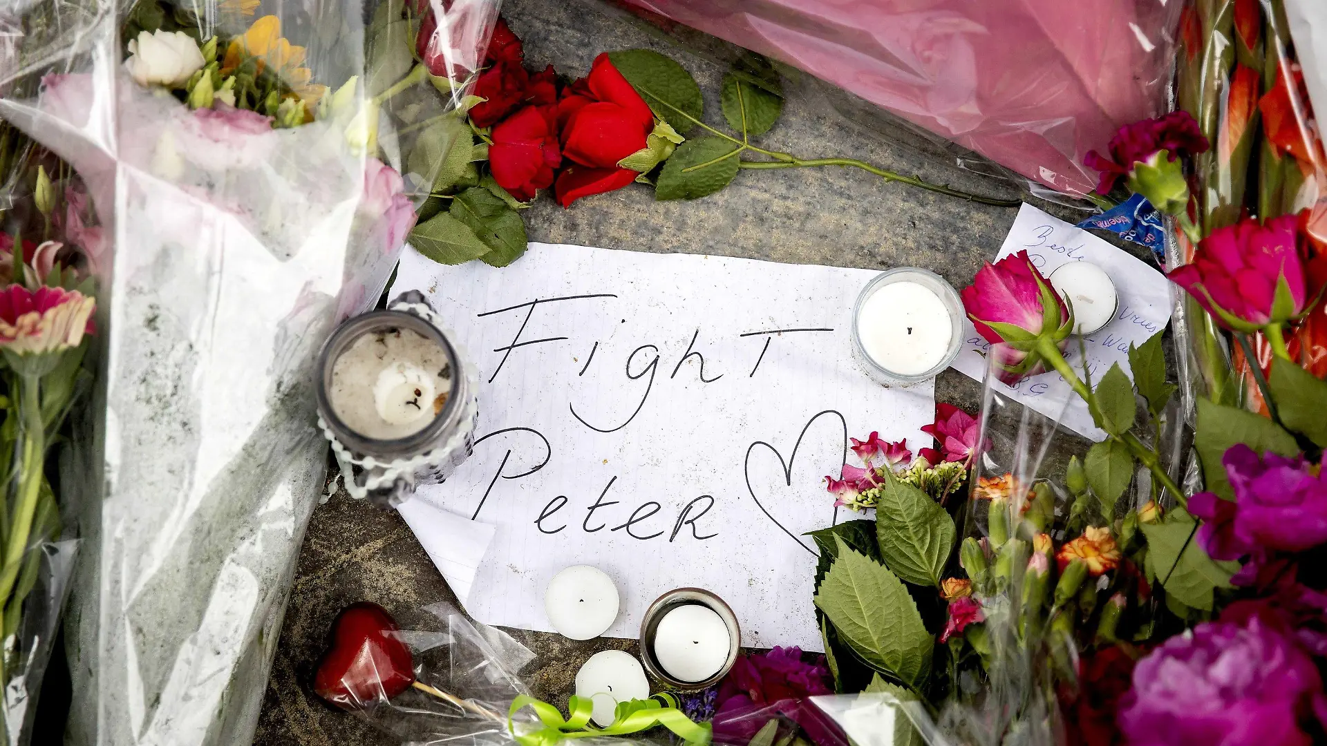 07.07.2021, Niederlande, Amsterdam: Blumen, Kerzen und eine Botschaft mit "Fight Peter" liegen am Tatort. Der auch international bekannte Kriminalreporter Peter R. de Vries war am Dienstagabend an dieser Stelle niedergeschossen und lebensgefährlich verletzt worden. Foto: Koen Van Weel/ANP/dpa +++ dpa-Bildfunk +++