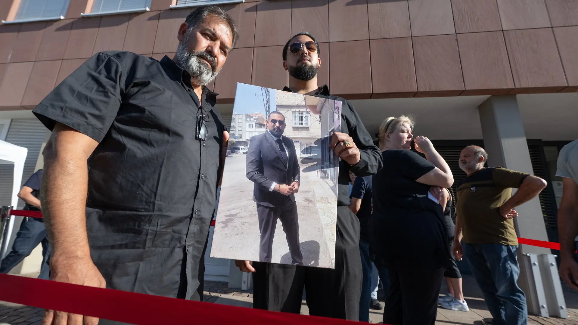 Erdal Calar, Vater des getöteten Zugbegleiters Serkan Calar wartet mit seinem Sohn Eray auf Einlass in das Landgericht. Dabei halten sie ein Foto des getöteten Serkan in den Händen.