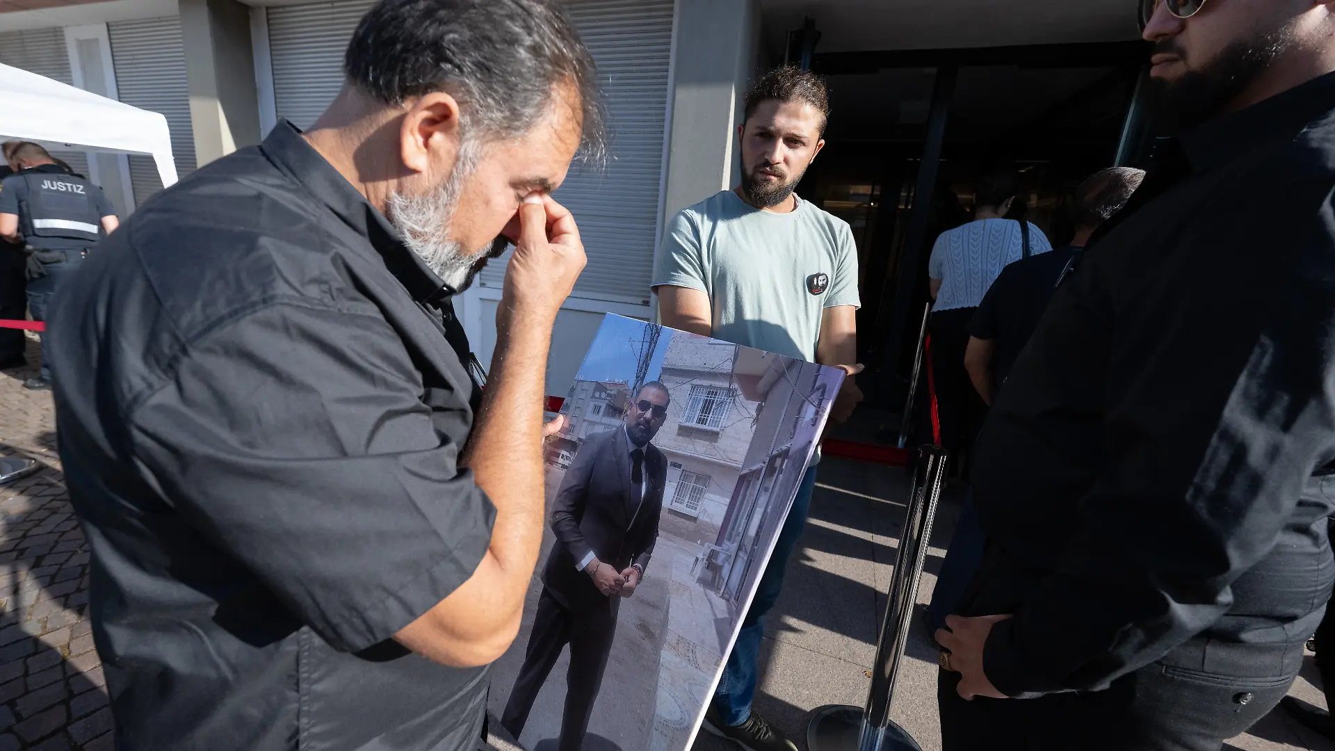 Weinend wartet Erdal Calar, Vater des getöteten Zugbegleiters Serkan Calar mit einem Bild seines Sohnes in der Hand auf Einlass in das Landgericht.