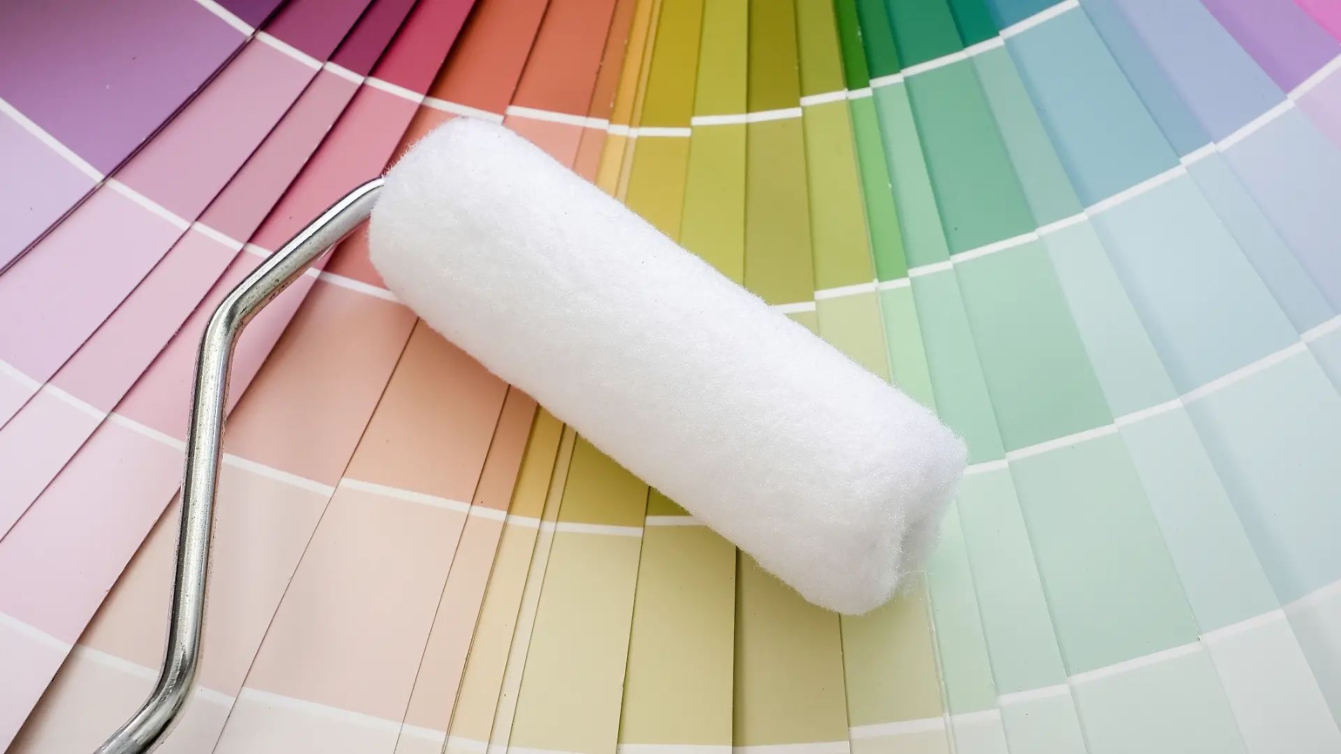 Paint roller ready for use, placed against a fanned-out color palette, representing renovation and interior design choices
