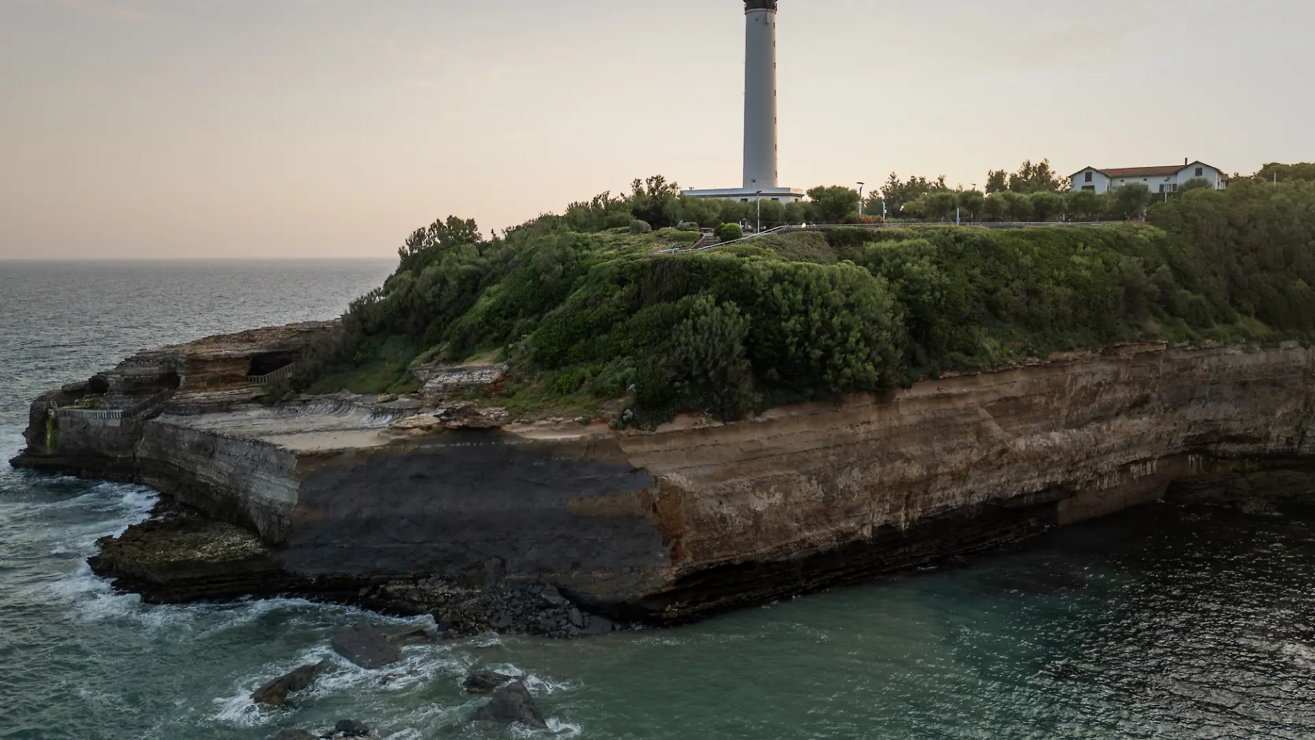 This aerial photograph shows the cliff facing Miramar beach, below the Biarritz lighthouse, on the morning after a cliff collapse, in Biarritz, south-western France, on June 25, 2026. A section of cliff approximately 2,000 square metres in size fell into the sea on the evening of June 24. The body of one victim was found, authorities said shortly before 11 pm, while another person was still missing. (Photo by Philippe LOPEZ / AFP)
