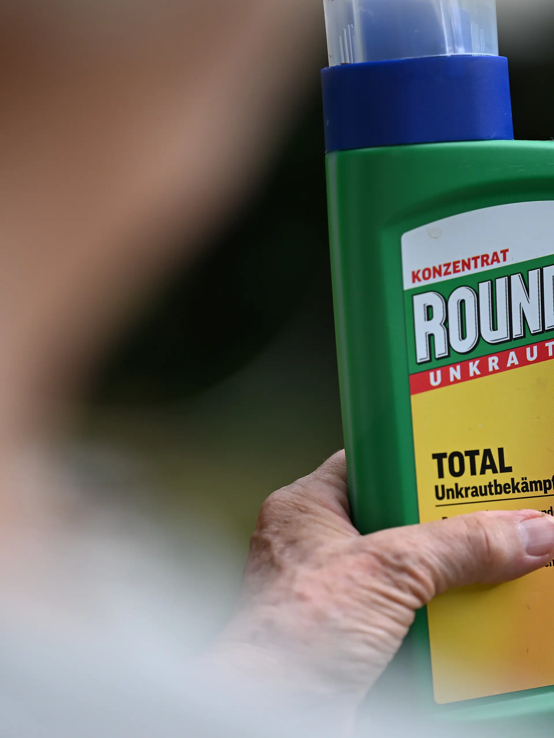 Eine Frau hält in ihrem Garten eine Flasche des Unkrautvernichters Roundup mit dem Wirkstoff Glyphosat von Bayer in der Hand (gestellte Szene). Die USA haben Glyphosat als unverzichtbar für die Ernährung und Verteidigung der USA eingestuft. (zu dpa: «Trump möchte Glyphosat-Produktion für US-Landwirte absichern») +++ dpa-Bildfunk +++