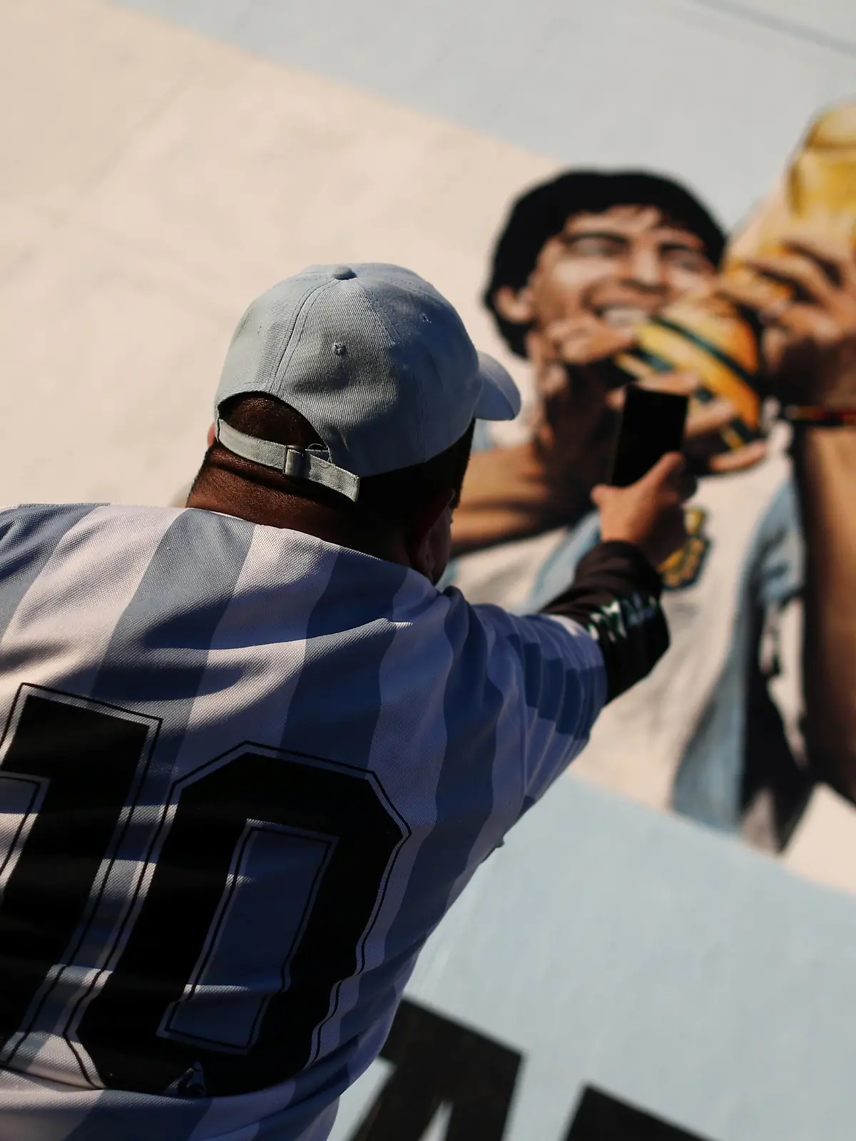 A fan of Argentine soccer superstar Diego Armado Maradona takes a picture of a mural as he celebrates the idol's 35th anniversary of the "goal of the century", against England during the 1986 World Cup played in Mexico, in Buenos Aires, Argentina June 22, 2021. REUTERS/Agustin Marcarian
