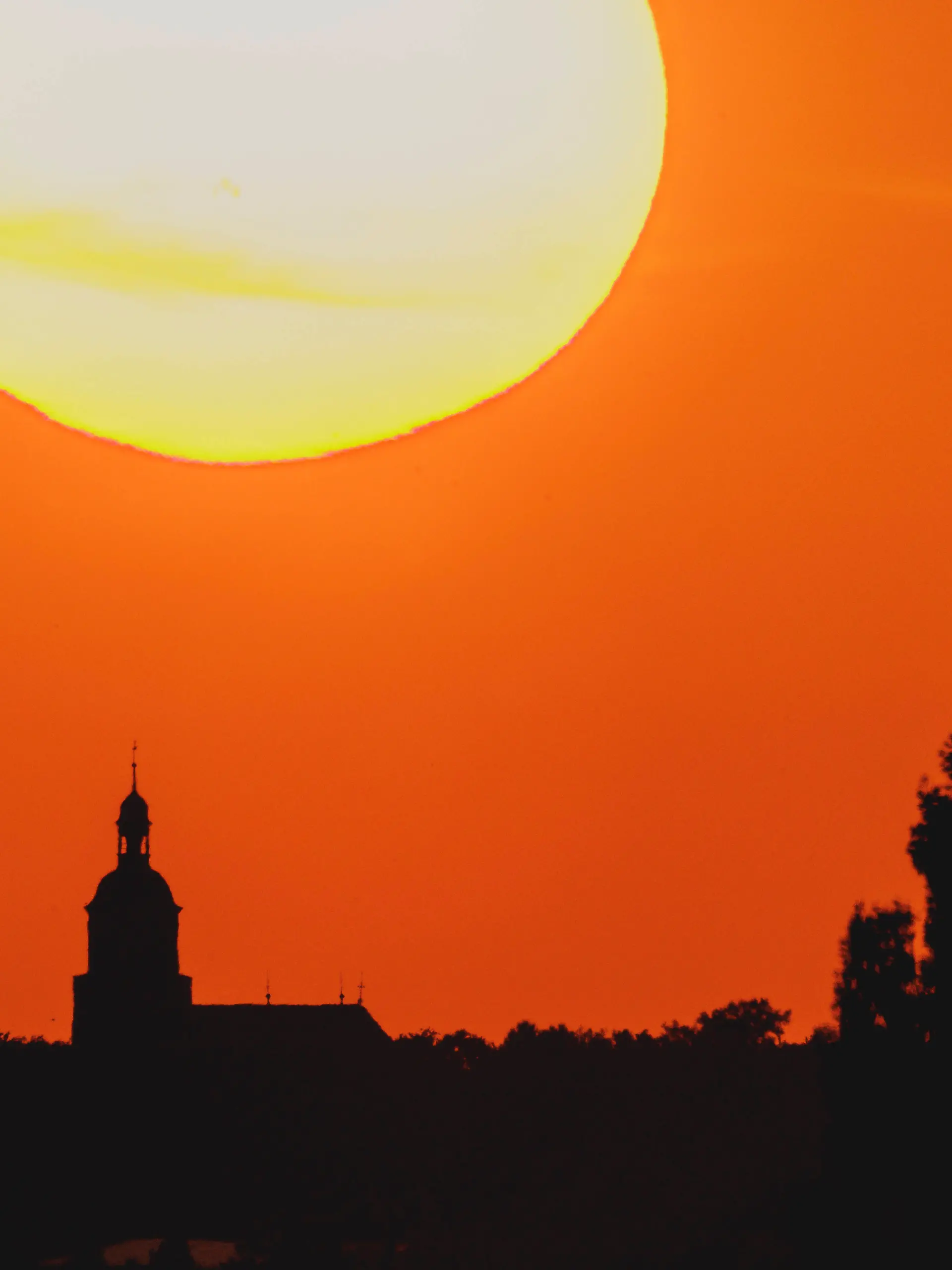Eine Kirche zeichnet sich ab vor der untergehenden Sonne in Malschwitz, 26.06.2026. Deutschland durchlebt eine grosse Hitzewelle mit teils ueber 40 Grad. 