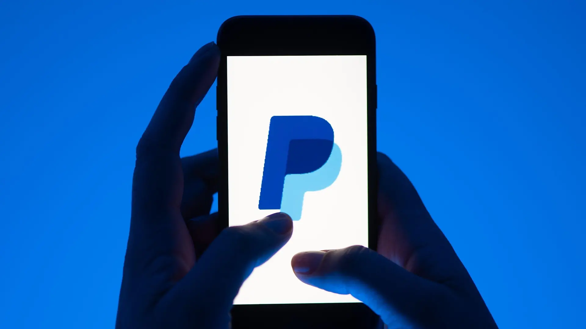 ARCHIV - 12.05.2022, Sachsen, Dresden: Eine Frau hält ein Smartphone mit dem Logo des Bezahldienst Paypal. (gestellte Szene) Der Online-Bezahldienst Paypal hat den Gewinn im ersten Quartal kräftig gesteigert und seine Ziele für das Gesamtjahr erhöht. (zu dpa: «Paypal hebt Jahresziel nach Gewinnsprung im Auftaktquartal an») Foto: Sebastian Kahnert/dpa +++ dpa-Bildfunk +++
