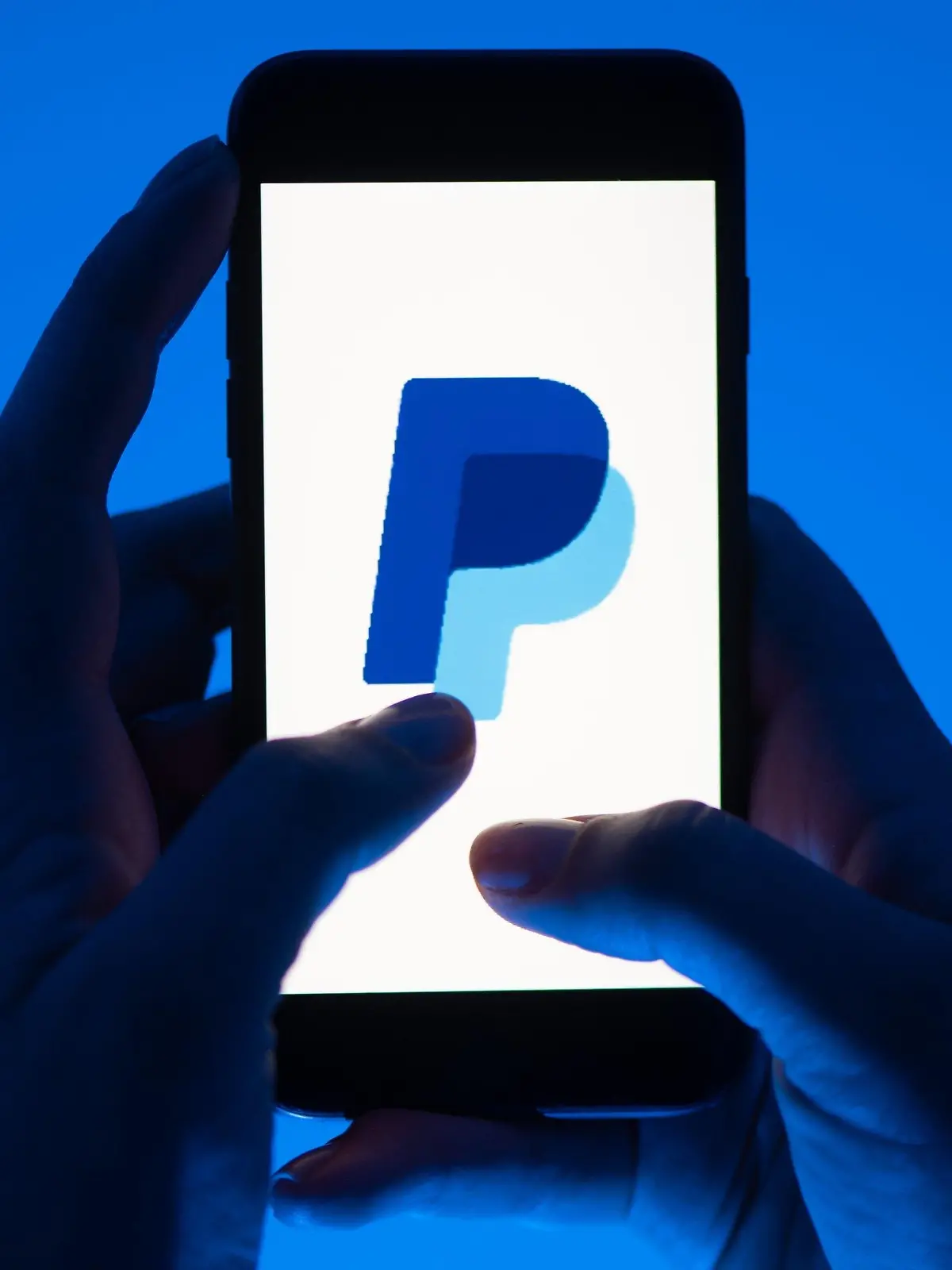 ARCHIV - 12.05.2022, Sachsen, Dresden: Eine Frau hält ein Smartphone mit dem Logo des Bezahldienst Paypal. (gestellte Szene) Der Online-Bezahldienst Paypal hat den Gewinn im ersten Quartal kräftig gesteigert und seine Ziele für das Gesamtjahr erhöht. (zu dpa: «Paypal hebt Jahresziel nach Gewinnsprung im Auftaktquartal an») Foto: Sebastian Kahnert/dpa +++ dpa-Bildfunk +++