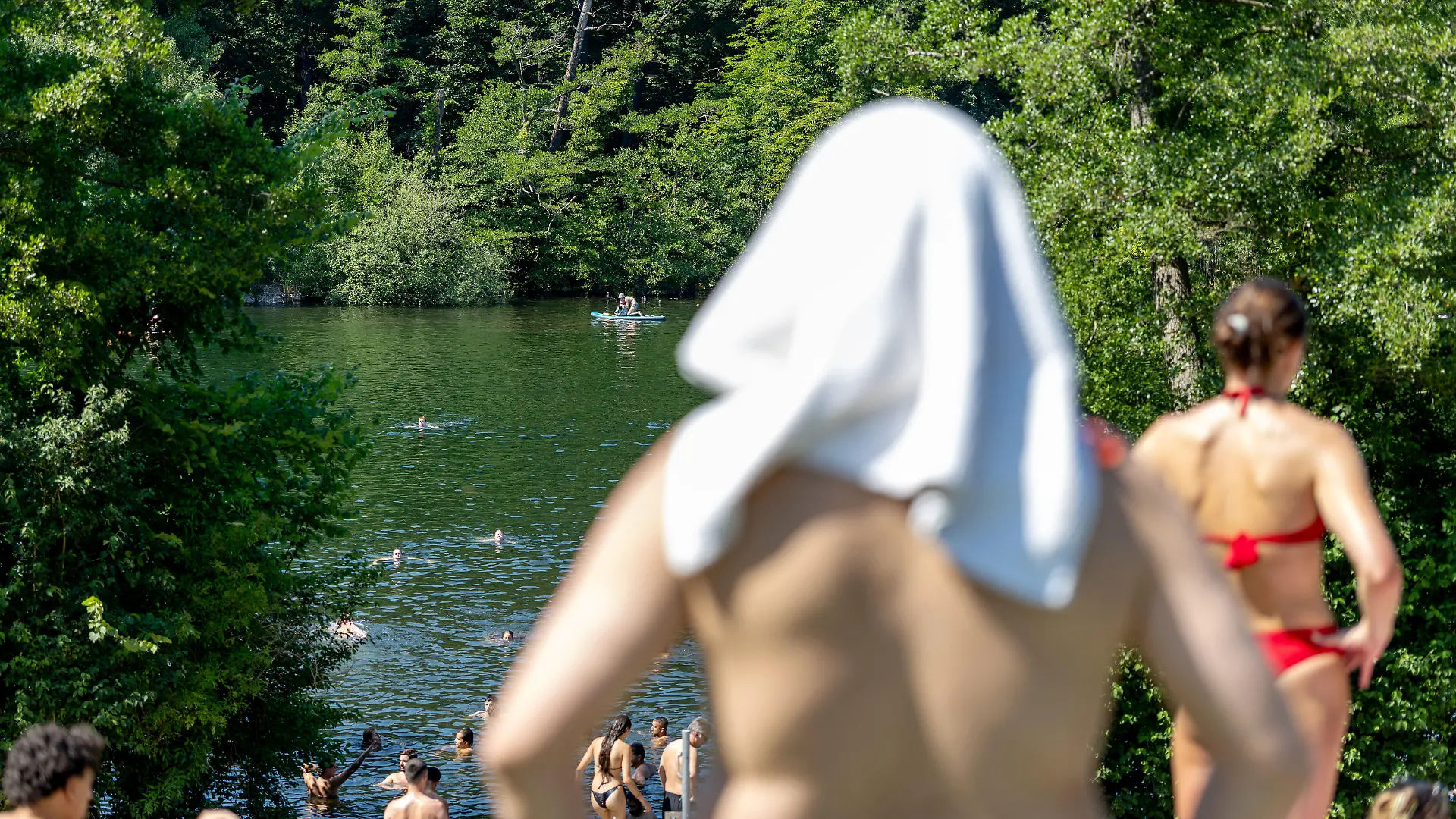 Berlin, Deutschland -27.6.2026: Menschen, darunter ein Mann mit Handtuch über seinem Kopf, bei 38 Grad Celsius am Schlachtensee in Berlin. Nach 41,3°C in Saarbrücken am Freitag wurde am heutigen Samstag mit 41,5°C in Möckern-Drewitz in Sachsen-Anhalt erneut ein Höchstwert in Deutschland aufgezeichnet.