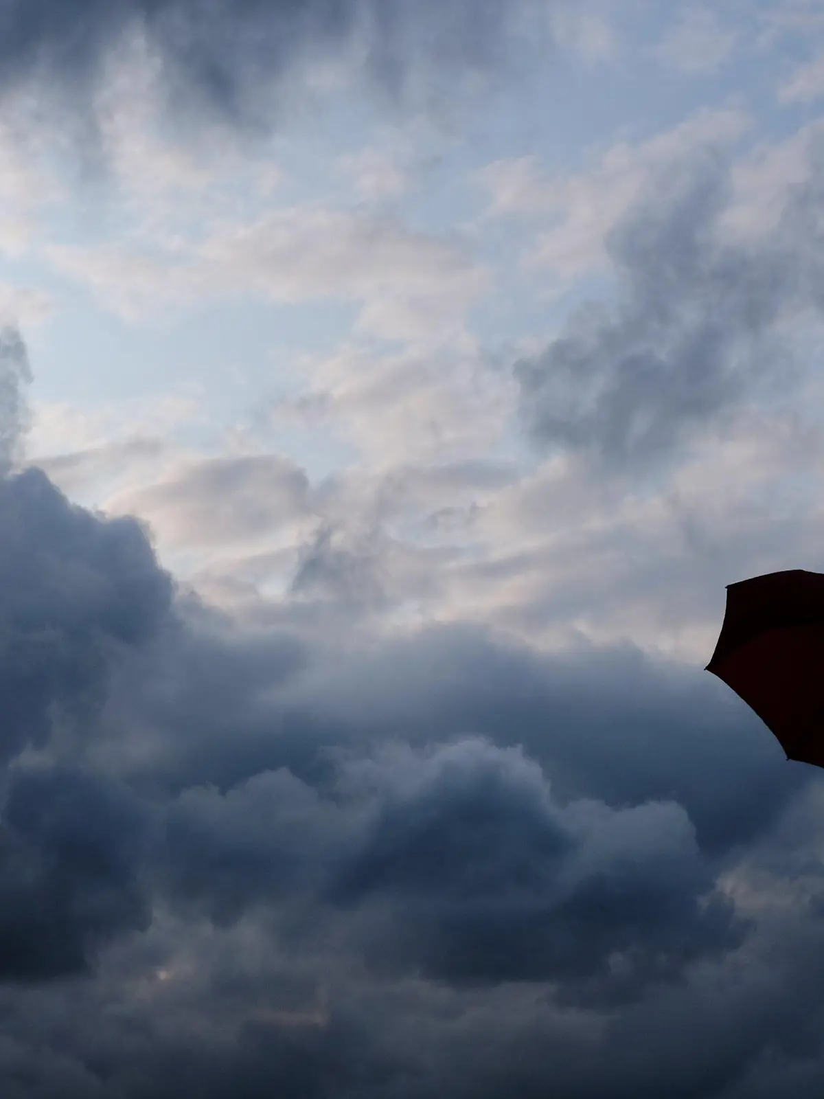 ARCHIV - 12.07.2019, Nordrhein-Westfalen, Duisburg: Ein Mann geht mit einem Regenschirm vor aufziehenden dunklen Wolken spazieren.  Nach ersten sonnigen Frühlingstagen schwenkt das Wetter in Nordrhein-Westfalen schon wieder um. Heftiger Starkregen, stürmische Böoen und kleinkörniger Hagel sind möglich. (zu dpa «Prognose: «Unwetter möglich» mit Starkregen, Sturm und Hagel in NRW») Foto: Martin Gerten/dpa +++ dpa-Bildfunk +++