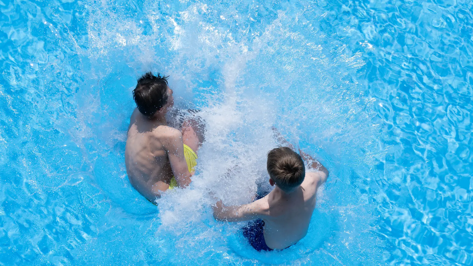 Zwei Jungen springen im Freibad Zacke vom Beckenrand ins Wasser. Aufgrund des schönen Frühlingswetters startet das Erlebnisbad ab sofort in die Badesaison.