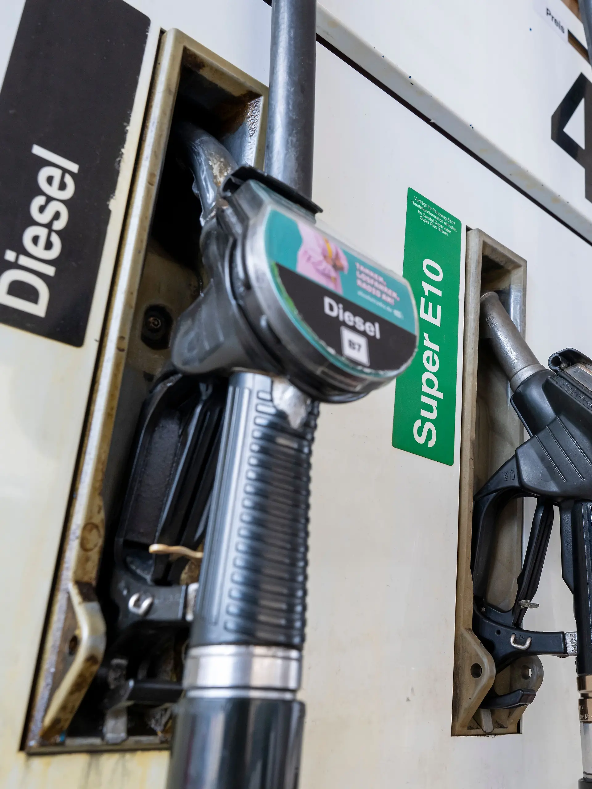Zapfpistolen für Kraftstoff hängen an einer Tankstelle in der Halterung.