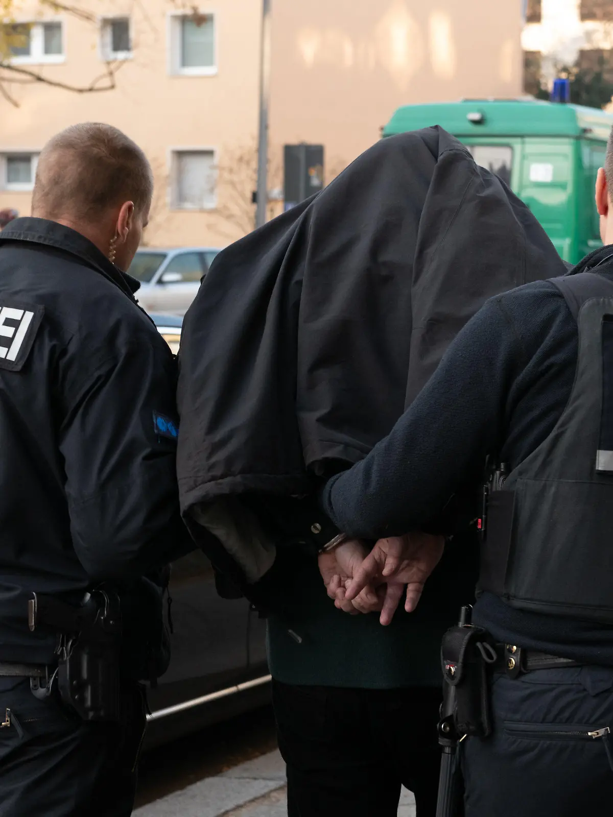 ARCHIV - 07.11.2018, Berlin: Polizeibeamte führen mit Handschellen einen festgenommenen Mann nach einer Razzia in einem Wohnhaus in Tempelhof ab. Im Kampf gegen kriminelle Mitglieder von Clans hat Berlin eine Konferenz mit nationalen und internationalen Experten organisiert. (zu "Im Kampf gegen Clan-Kriminalität: Große Konferenz in Berlin") Foto: Paul Zinken/dpa +++ dpa-Bildfunk +++