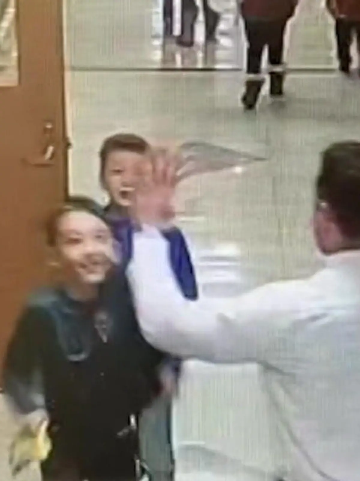 Schulleiter verteilt Highfives an seine Grundschüler.