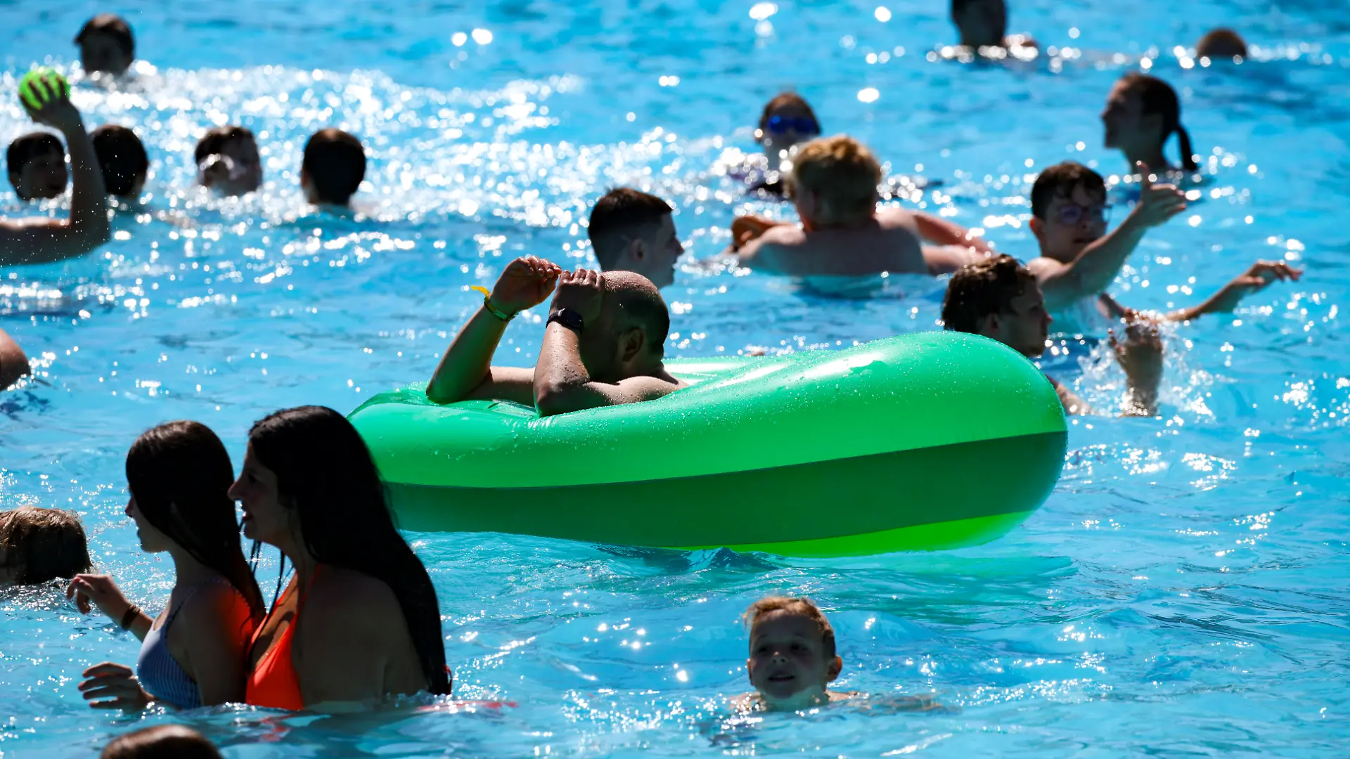 Besucher schwimmen im Wasser im Grugabad in Essen.