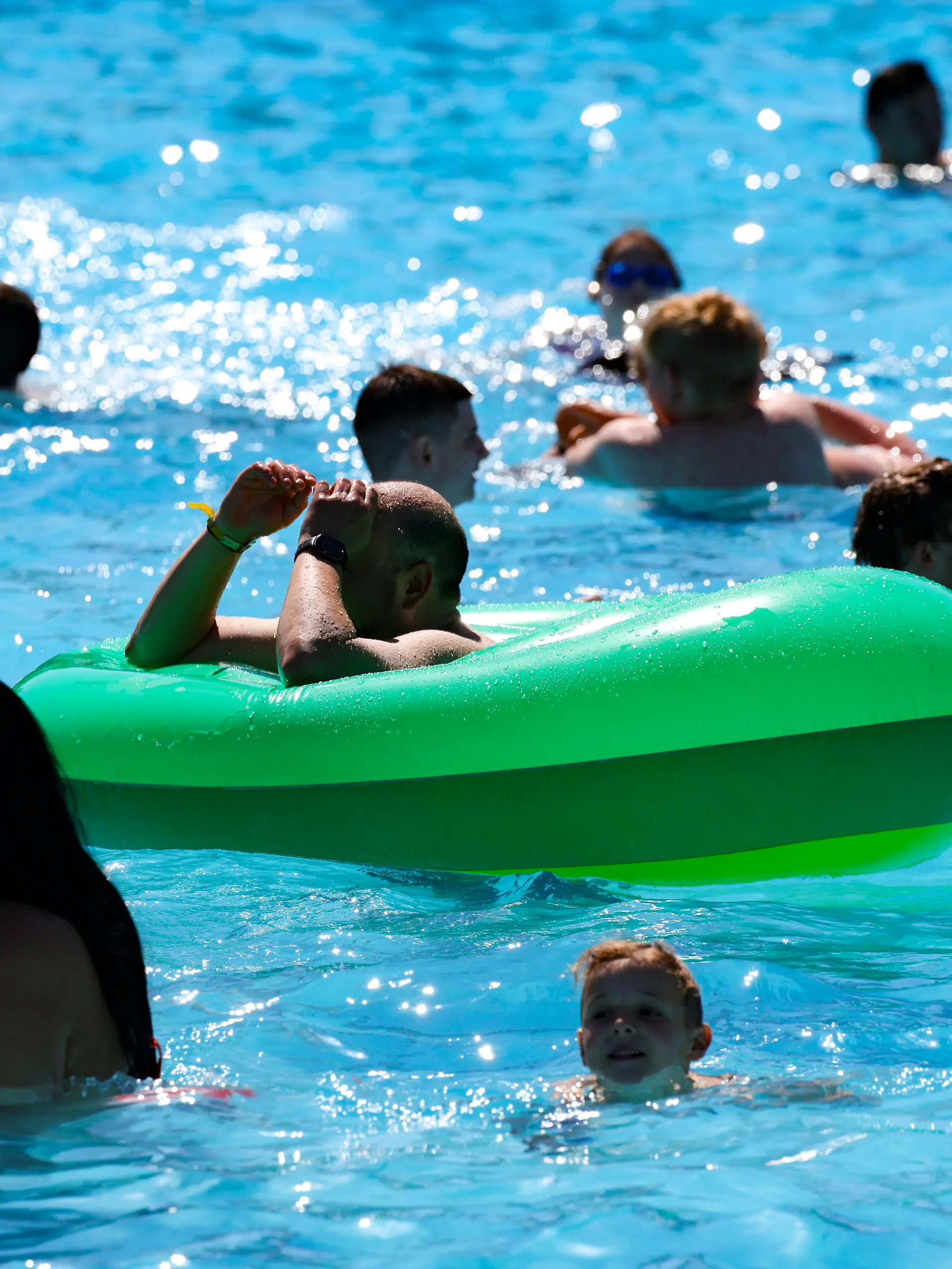Besucher schwimmen im Wasser im Grugabad in Essen.