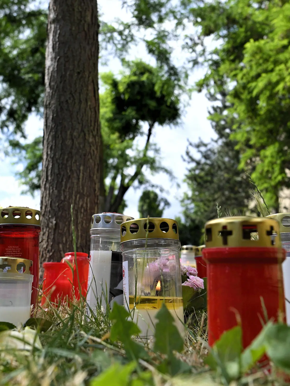 30.06.2021, Österreich, Wien: Kerzen und Blumen liegen am Fundort der Leiche eines erst 13 Jahre alten Mädchens. Nach dem Fund der Leiche eines 13-jährigen Mädchens in Wien hat die Polizei zwei Männer festgenommen. Die beiden Verdächtigen sind laut Behörden 16 und 18 Jahre alt. Foto: Herbert Neubauer/APA/dpa +++ dpa-Bildfunk +++