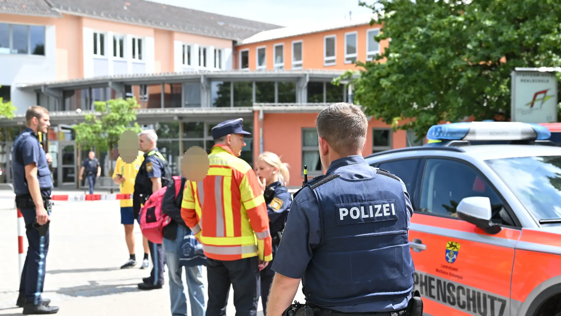 Einsatzkräfte von Polizei und Rettungsdiensten stehen vor dem Welfen-Gymnasium.