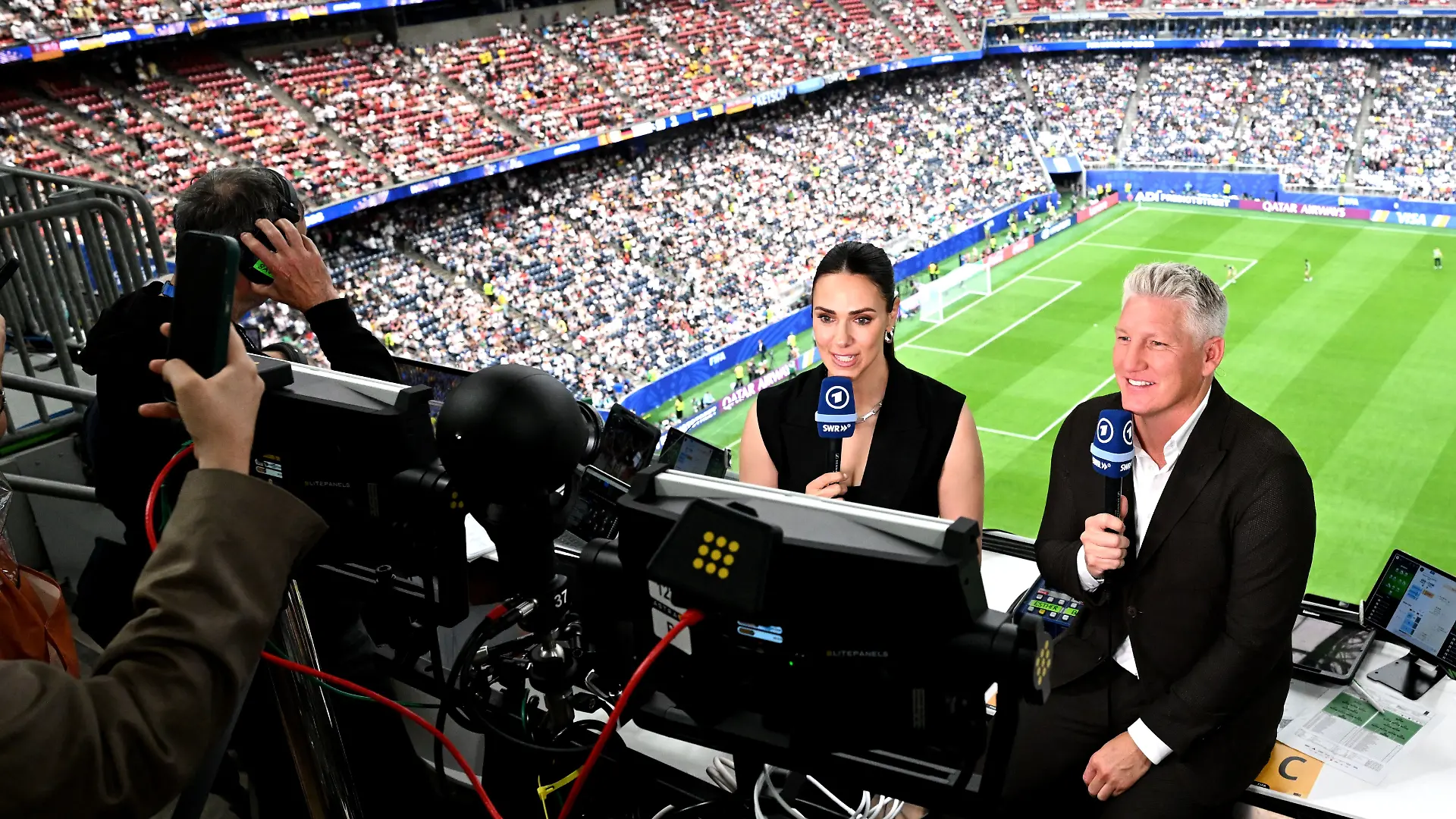 ARCHIV - 14.06.2026, USA, Houston: Fußball, Männer: WM, Deutschland - Curaçao, Vorrunde, Gruppe E, 1. Spieltag, Houston-Stadion, Weltmeister und TV-Experte Bastian Schweinsteiger (r) und Moderatorin Esther Sedlaczek. ACHTUNG: Gemäß den Auflagen der FIFA dürfen die Bilder ausschließlich zur redaktionellen Verwendung genutzt werden. Eine kommerzielle Nutzung ist ausgeschlossen. Zudem dürfen keine videoähnlichen Sequenzen erstellt werden, und es dürfen keine Veränderungen weder im Vordergrund noch im Hintergrund am Bild vorgenommen werden. (zu dpa: ««Geht nicht»: Schweinsteiger kritisiert FIFA im Fall Balogun») Foto: Federico Gambarini/dpa +++ dpa-Bildfunk +++