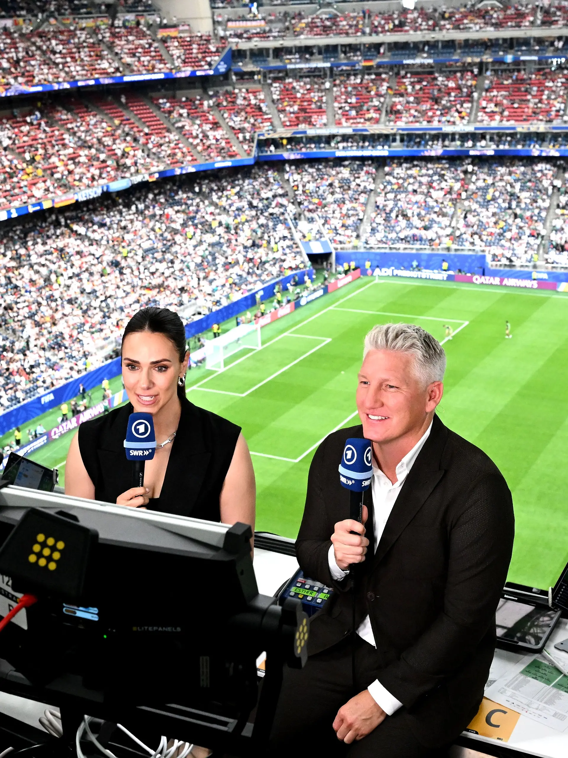 ARCHIV - 14.06.2026, USA, Houston: Fußball, Männer: WM, Deutschland - Curaçao, Vorrunde, Gruppe E, 1. Spieltag, Houston-Stadion, Weltmeister und TV-Experte Bastian Schweinsteiger (r) und Moderatorin Esther Sedlaczek. ACHTUNG: Gemäß den Auflagen der FIFA dürfen die Bilder ausschließlich zur redaktionellen Verwendung genutzt werden. Eine kommerzielle Nutzung ist ausgeschlossen. Zudem dürfen keine videoähnlichen Sequenzen erstellt werden, und es dürfen keine Veränderungen weder im Vordergrund noch im Hintergrund am Bild vorgenommen werden. (zu dpa: ««Geht nicht»: Schweinsteiger kritisiert FIFA im Fall Balogun») Foto: Federico Gambarini/dpa +++ dpa-Bildfunk +++