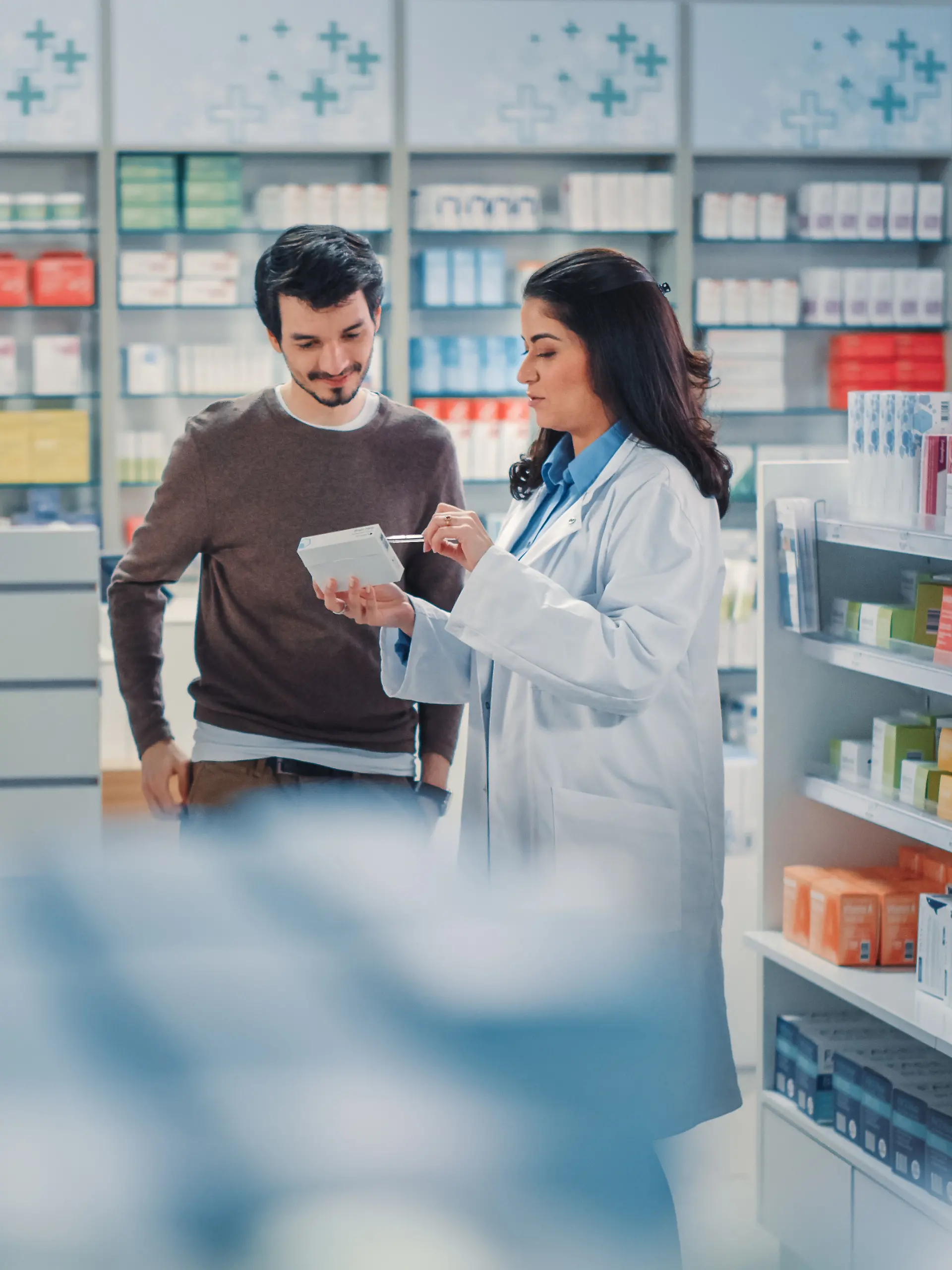 Junger Mann lässt sich in der Apotheke beim Medikamenten-Kauf beraten.