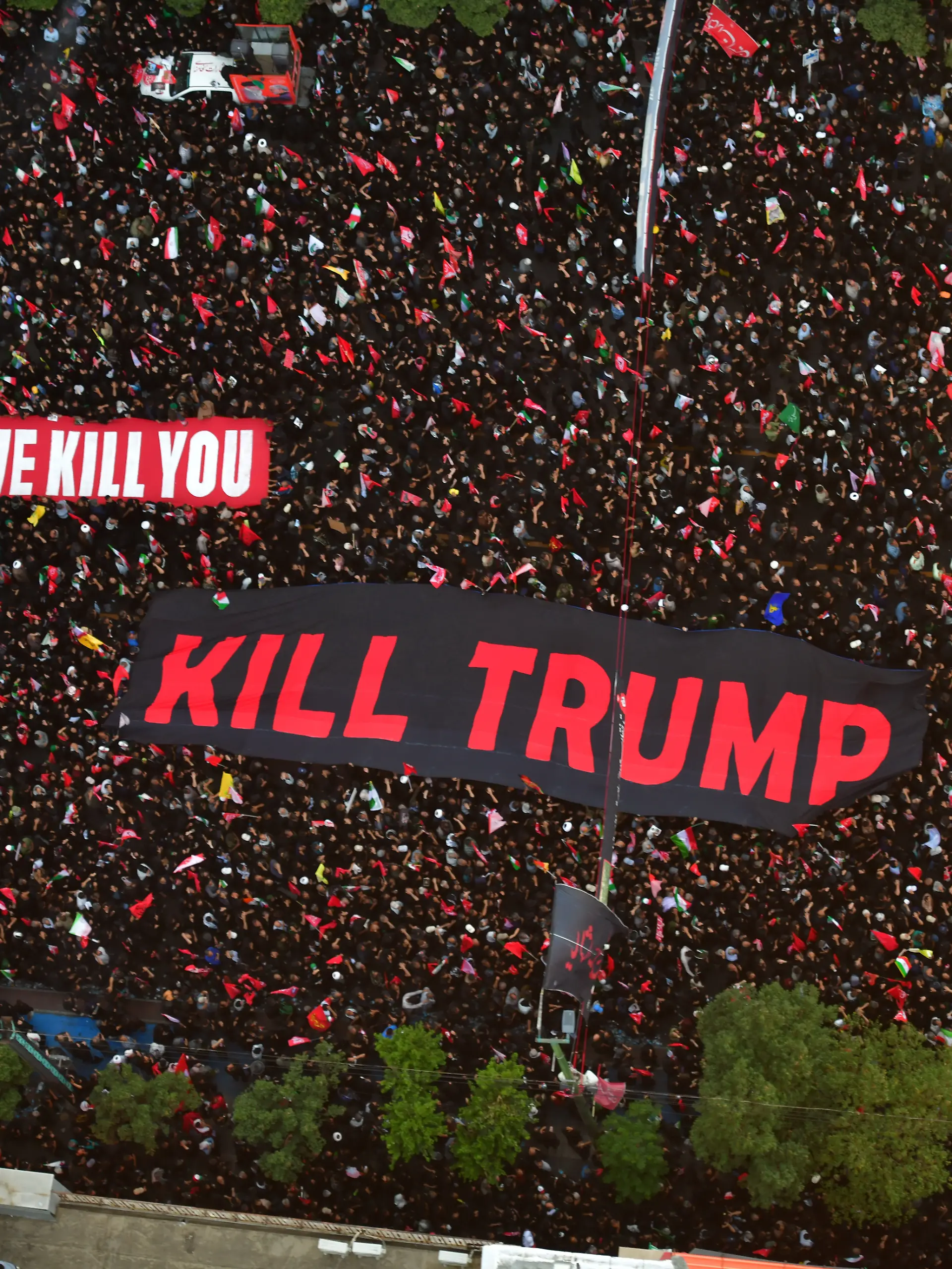 Mashhad, Iran  July 9, 2026: Participants seen holding a banner bearing the English-language message, "We will kill Trump." Thousands of people gather on Imam Reza Boulevard for a final farewell to Ayatollah Khamenei as his coffin is carried toward the Imam Reza Shrine. Many mourners wave red flags, which participants say symbolize a call for revenge against those they hold responsible for his death, alongside other religious flags associated with the Shia community. The procession draws large crowds lining the route leading to the shrine.//FARNOOD_sipa.12870/Credit:Heidari/SIPA/2607101650