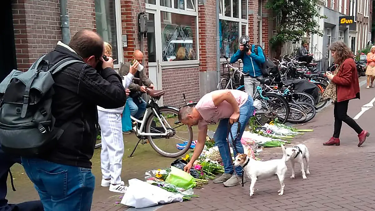 A man places flowers where journalist Peter R. de Vries has been shot, Wednesday, July, 7, 2021 in Amsterdam. Peter R. de Vries, who is widely lauded for fearless reporting on the Dutch underworld, was shot Tuesday after making one of his regular appearances on a current affairs television show. It was an unusually brutal attack on a journalist in the Netherlands. (AP Photo/Molly Quell)