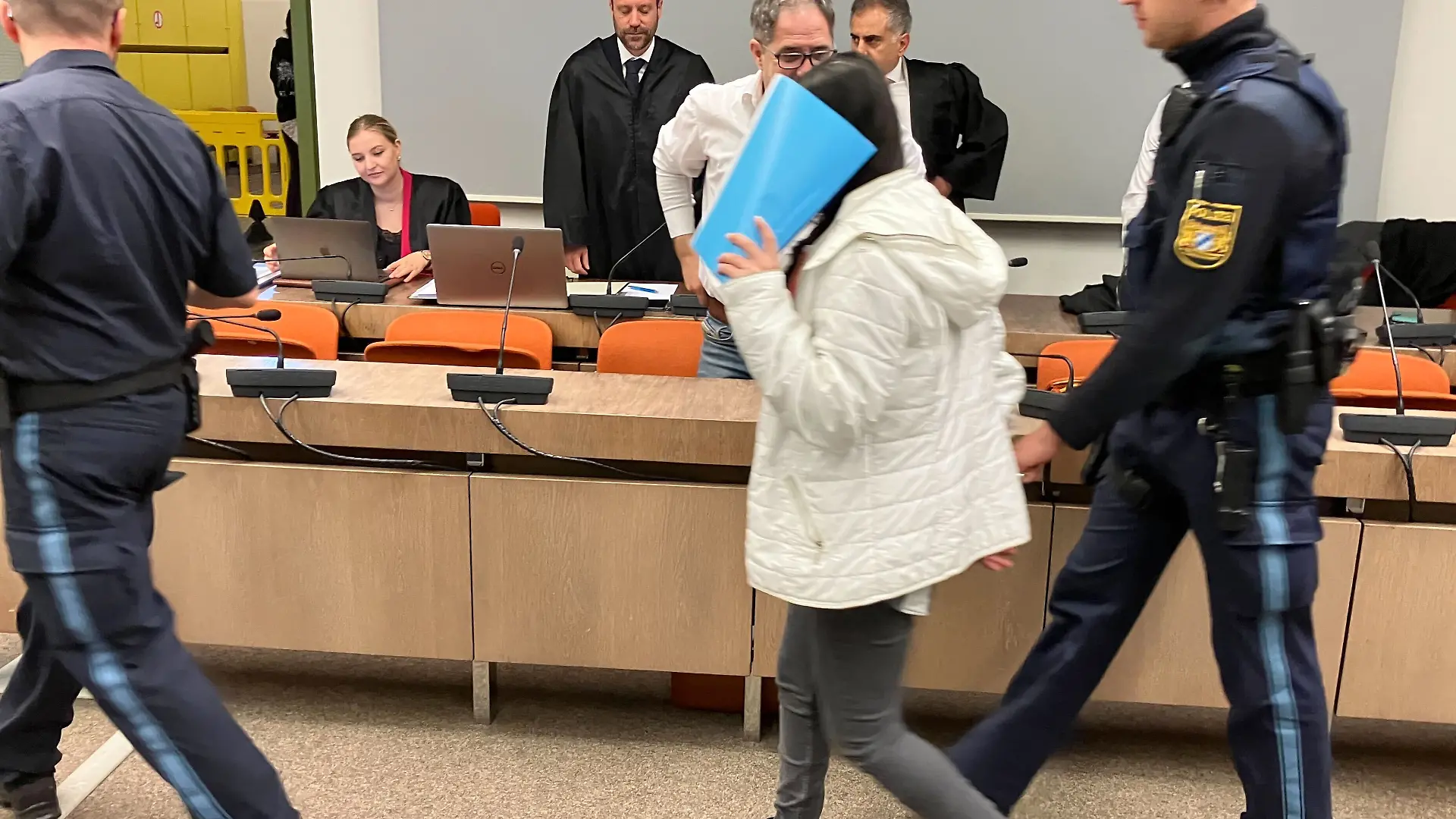 Justizbeamte bringen die angeklagte irakische Frau (M) in den Saal des Oberlandesgerichts. Das irakische Ehepaar ist angeklagt Versklavung, Vergewaltigung und Verbrechen gegen die Menschlichkeit. Das Paar soll laut Ermittlern als Teil der Terrororganisation Islamischer Staat (IS) zwei jesidische Mädchen als Sklavinnen gekauft, ausgebeutet und sexuell missbraucht haben.