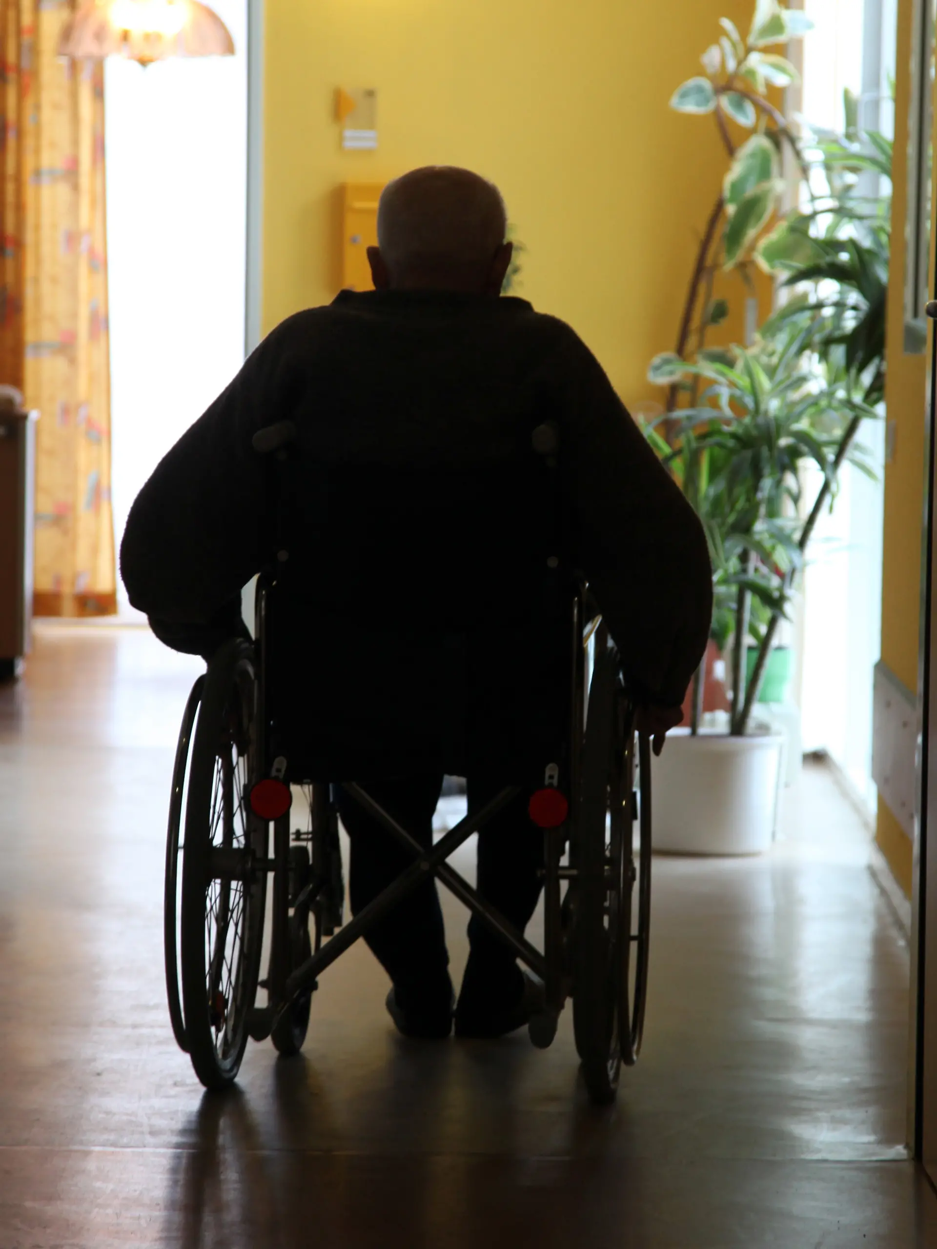 ARCHIV - Ein Bewohner im Rollstuhl fährt am 28.01.2010 in einem Pflegeheim über einen Flur. Der Bundesgerichtshof urteilt am 12.02.2014 über den Elternunterhalt. In dem Verfahren geht es um die Frage, ob erwachsene Kinder notfalls für die Heimkosten ihrer Eltern aufkommen müssen, selbst wenn diese den Kontakt schon vor langer Zeit abgebrochen und die Kinder nahezu enterbt haben. Foto: Jens Büttner/dpa +++ dpa-Bildfunk +++