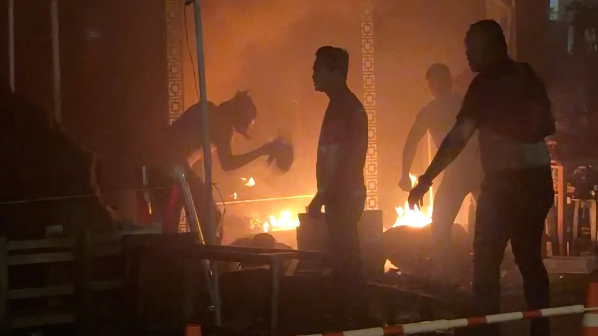 People try to douse a fire, following a deadly fire at a pub in Bangkok, Thailand, July 12, 2026, in this screengrab obtained from a video. VIDEO OBTAINED BY REUTERS/Handout via REUTERS THIS IMAGE HAS BEEN SUPPLIED BY A THIRD PARTY VERIFICATION: - Reuters verified the location from the buildings, highway and trees seen in the video, which matched archive and satellite imagery of the area. - The date when the video was recorded was verified by the metadata on the original video files.