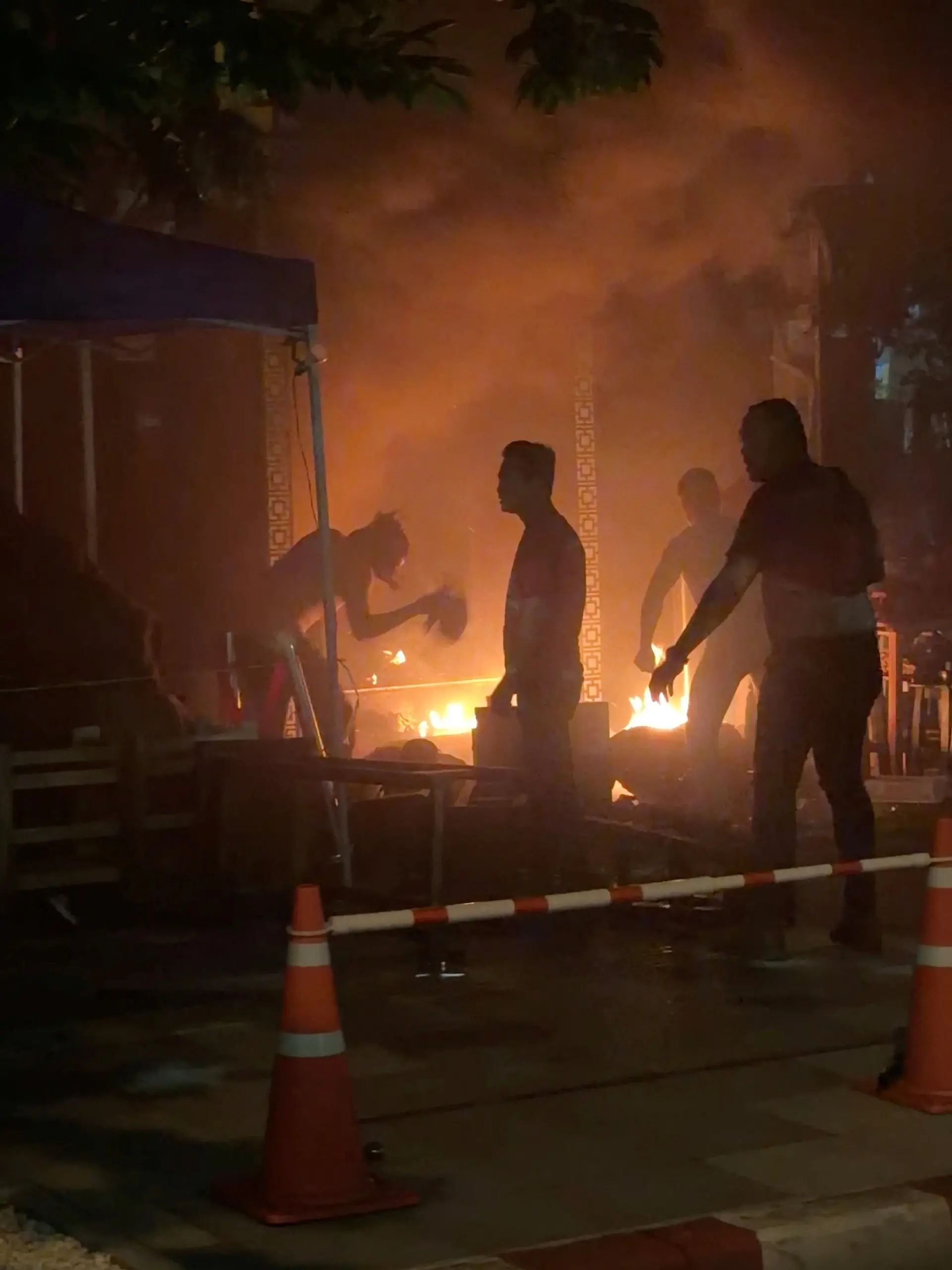People try to douse a fire, following a deadly fire at a pub in Bangkok, Thailand, July 12, 2026, in this screengrab obtained from a video. VIDEO OBTAINED BY REUTERS/Handout via REUTERS    THIS IMAGE HAS BEEN SUPPLIED BY A THIRD PARTY  VERIFICATION: - Reuters verified the location from the buildings, highway and trees seen in the video, which matched archive and satellite imagery of the area.  - The date when the video was recorded was verified by the metadata on the original video files.