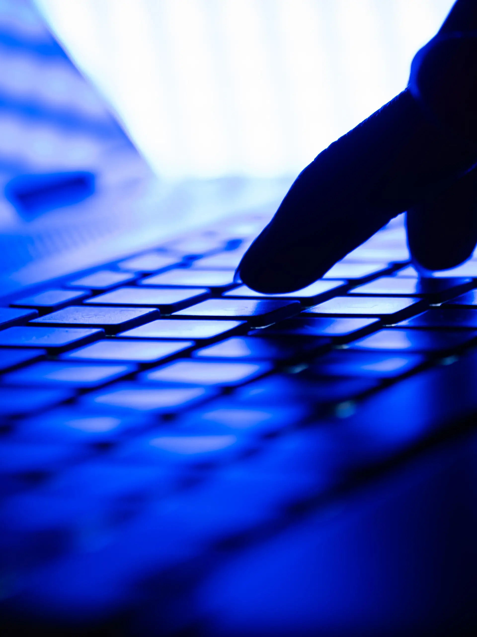 Hand auf einer Laptop Tastatur in einem dunklen Raum