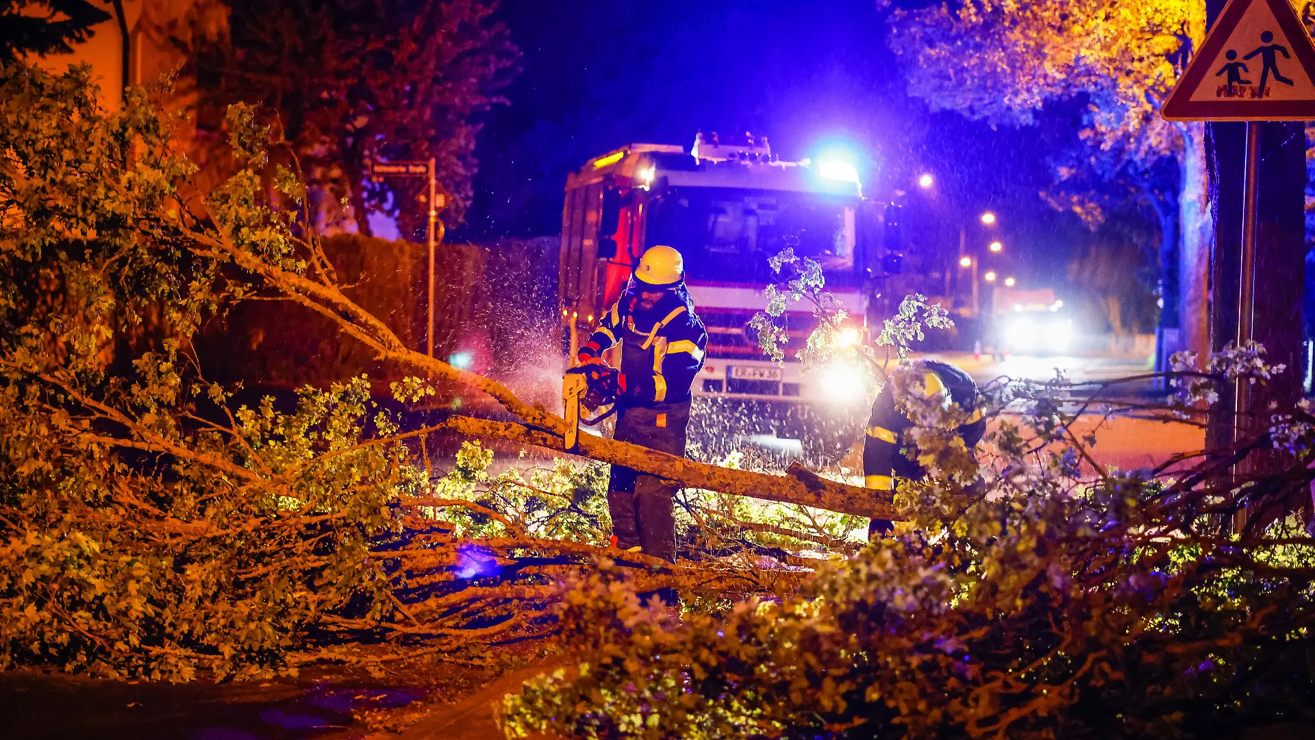 Einsatzkräfte der Feuerwehr zersägen mit einer Kettensäge einen umgestürzten Baum auf einer Straße im Regierungsbezirk Mittelfranken. Das über Deutschland hinweggezogene Unwetter hat am Montagabend in Teilen des Landes unter anderem Bäume umstürzen lassen und Dächer abgedeckt. +++ dpa-Bildfunk +++