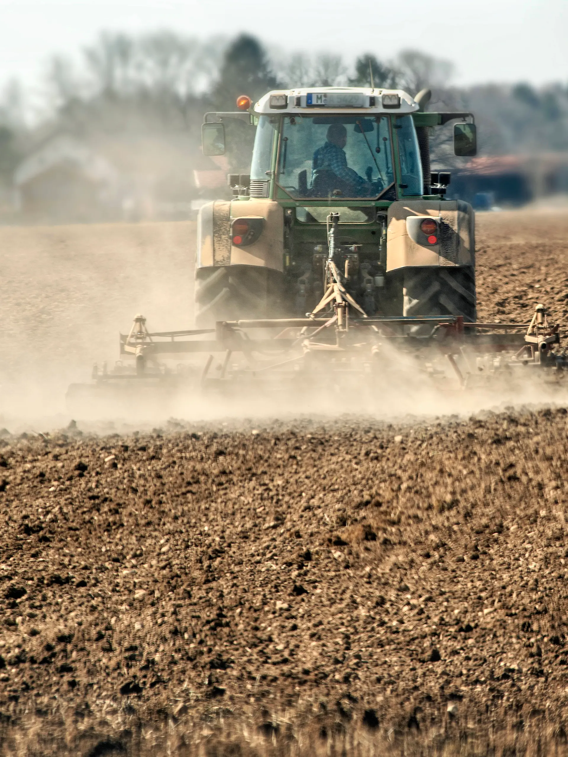 Landwirt mit Traktor auf dem Acker, wirbelt Staubwolken au