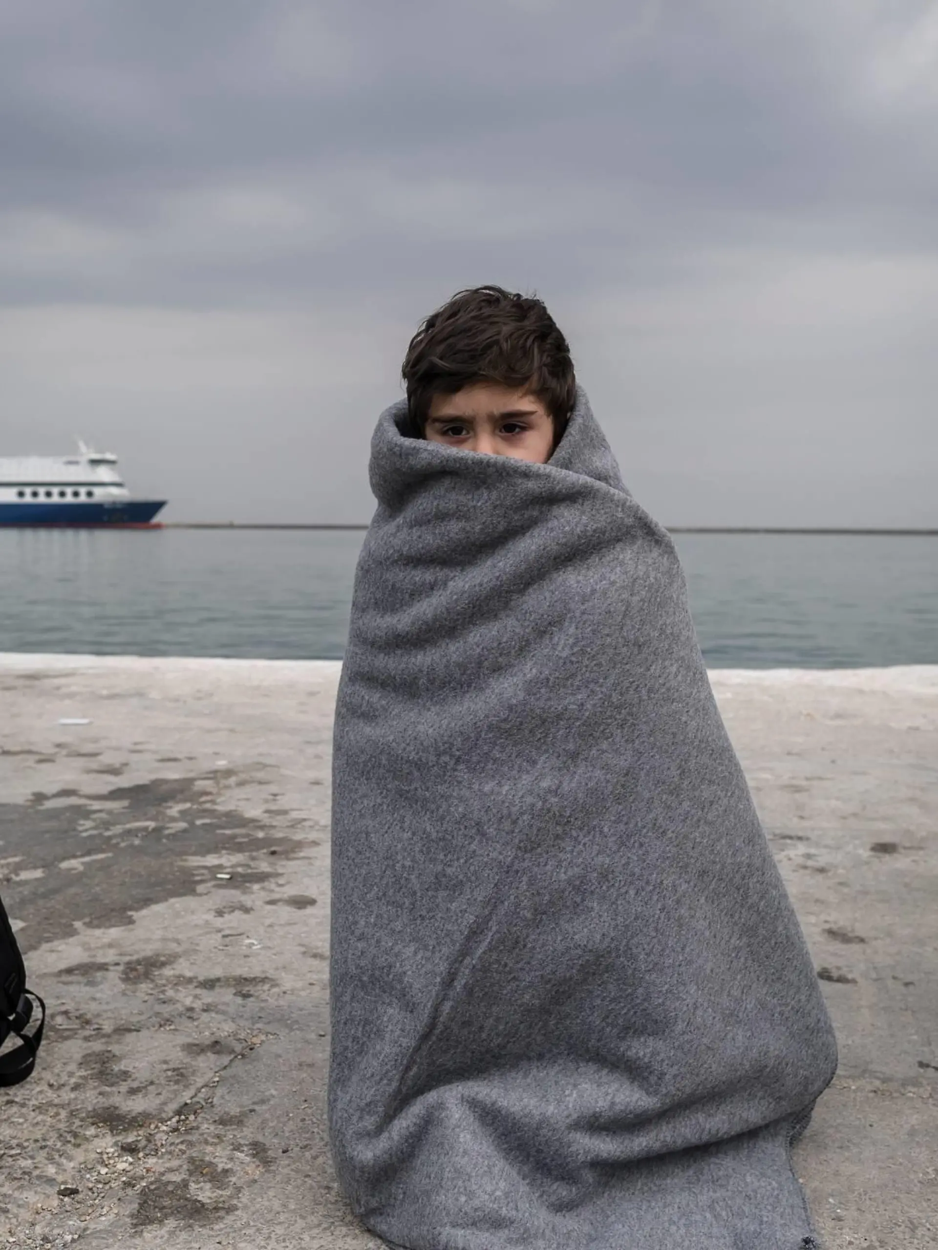  Flüchtlinge auf Lesbos - Fotostory Ein Kind steht am 02.03.2016 im Hafen von Mytilini, Griechenland eingehuellt in eine Decke. Europa stellt einen Fonds fuer eine humanitaere Krise innerhalb der EU mit 700 Millionen Euro Nothilfe bereit.