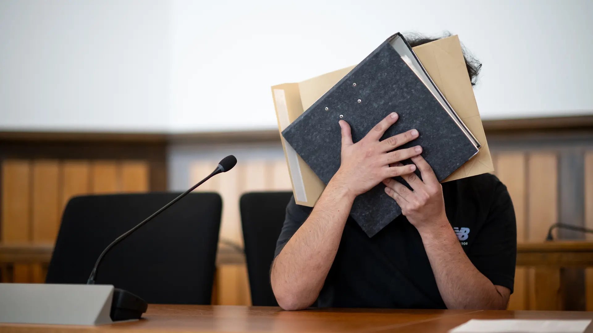 Der Angeklagte sitzt im Gerichtssaal und verdeckt sein Gesicht. Er soll sich mit gefälschten Urkunden eine Anstellung als Notfallsanitäter erschlichen und Patienten durch falsche Behandlung in Gefahr gebracht haben. Ein Patient ist gestorben. Die Anklage lautet Totschlag, gefährliche Körperverletzung sowie Urkundenfälschung. +++ dpa-Bildfunk +++