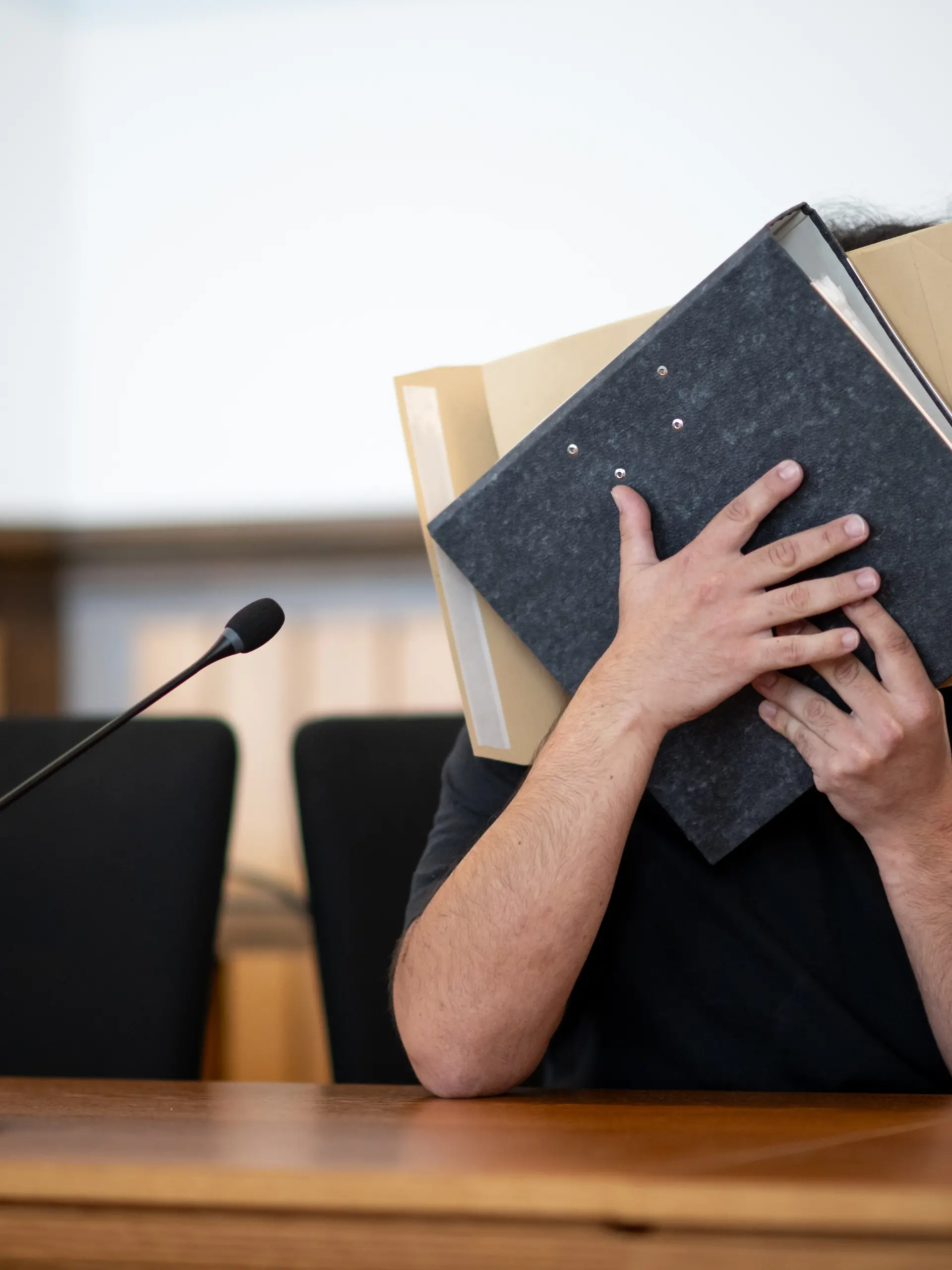 Der Angeklagte sitzt im Gerichtssaal und verdeckt sein Gesicht. Er soll sich mit gefälschten Urkunden eine Anstellung als Notfallsanitäter erschlichen und Patienten durch falsche Behandlung in Gefahr gebracht haben. Ein Patient ist gestorben. Die Anklage lautet Totschlag, gefährliche Körperverletzung sowie Urkundenfälschung. +++ dpa-Bildfunk +++