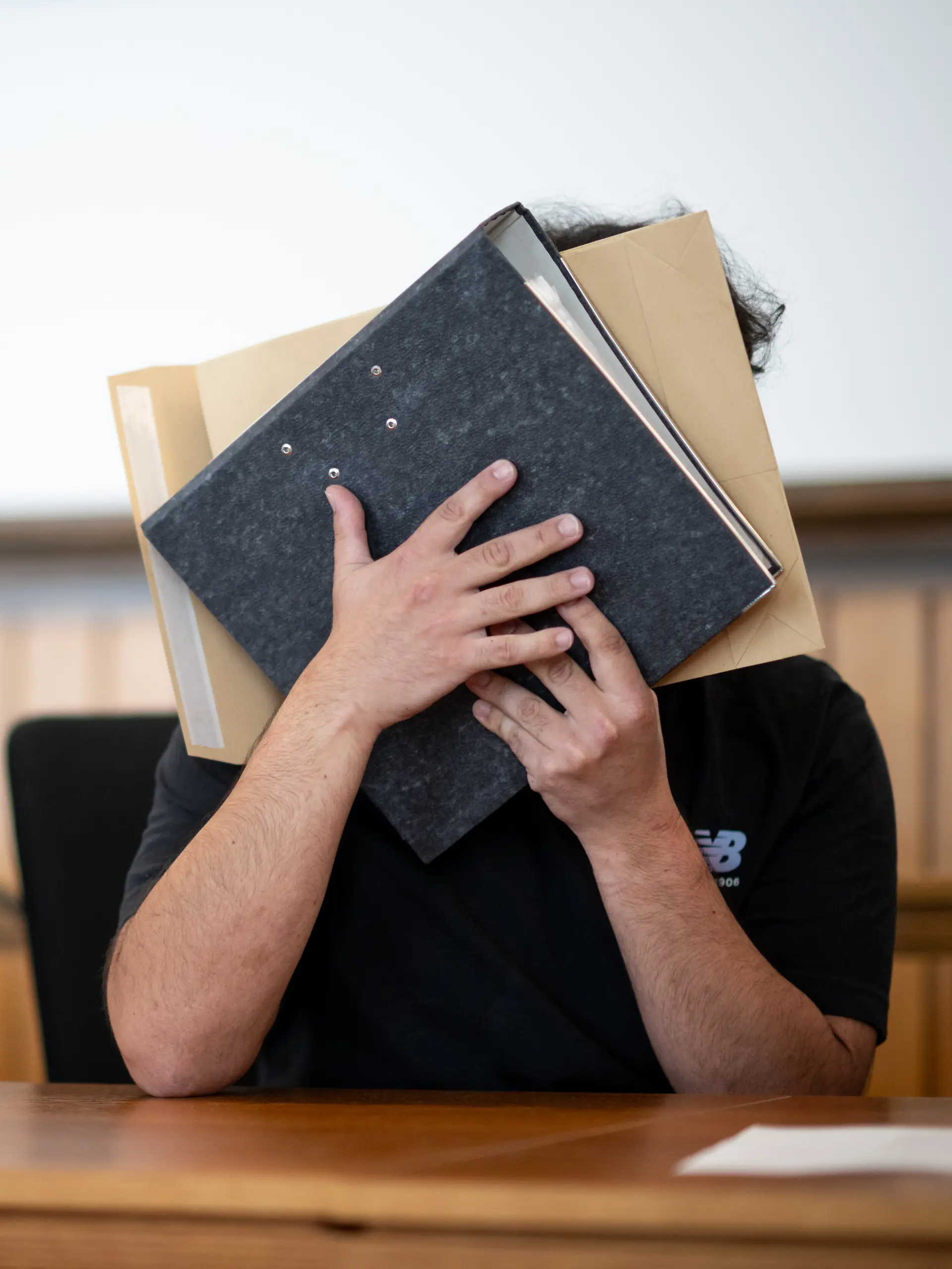 Der Angeklagte sitzt im Gerichtssaal und verdeckt sein Gesicht. Er soll sich mit gefälschten Urkunden eine Anstellung als Notfallsanitäter erschlichen und Patienten durch falsche Behandlung in Gefahr gebracht haben. Ein Patient ist gestorben. Die Anklage lautet Totschlag, gefährliche Körperverletzung sowie Urkundenfälschung. +++ dpa-Bildfunk +++