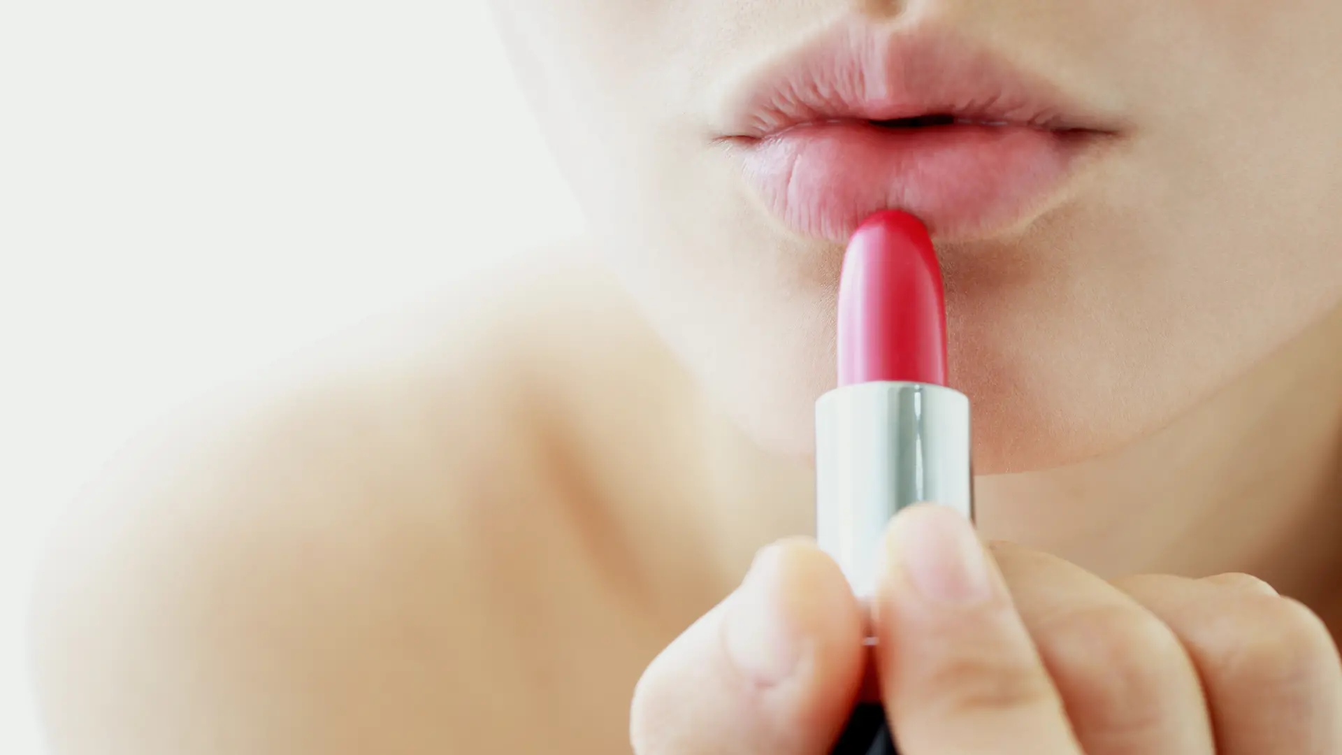 Junge Frau, die sich Lippenstift aufträgt