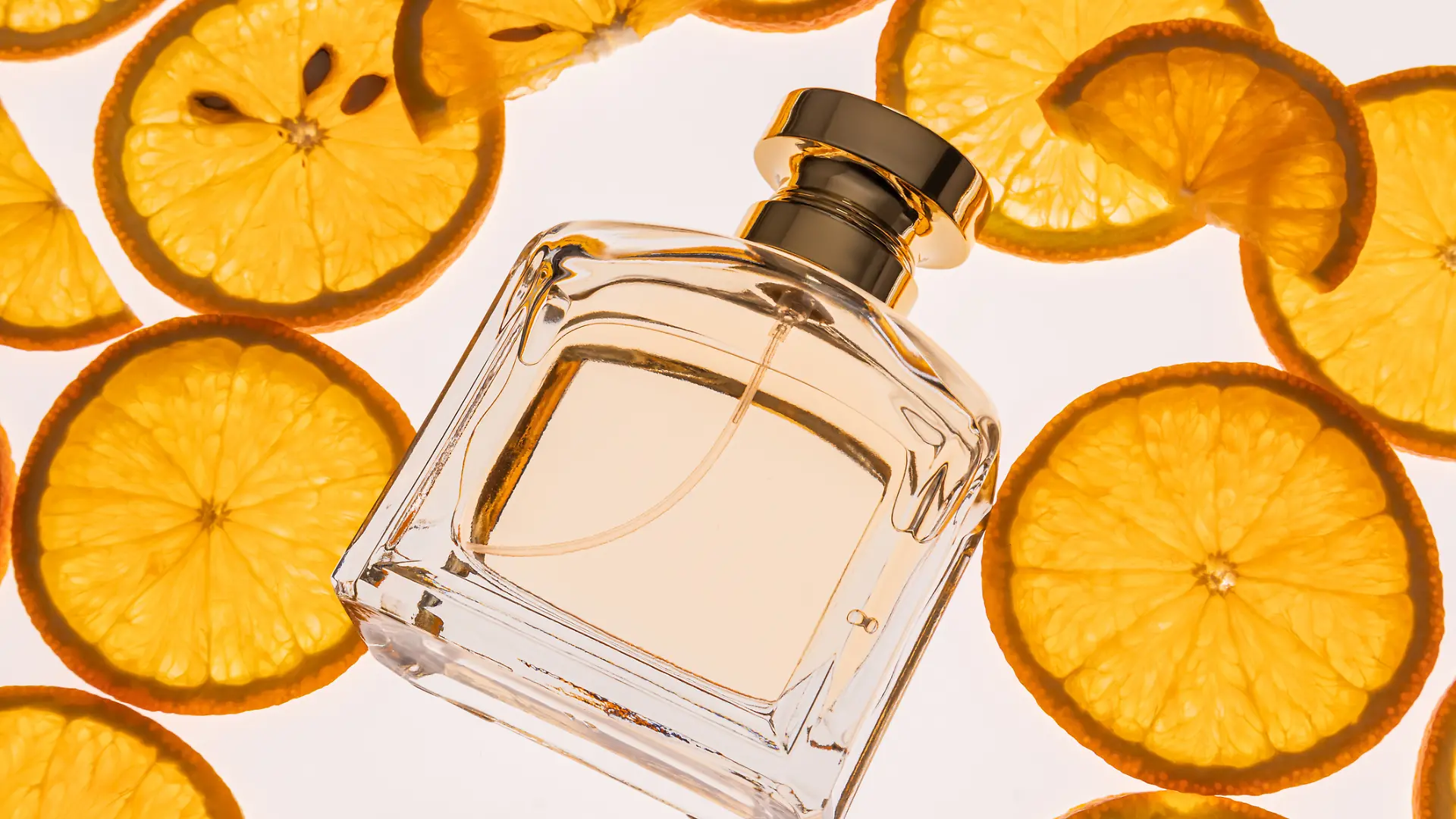 Eine Parfumflasche liegt neben Zitronenscheiben.
