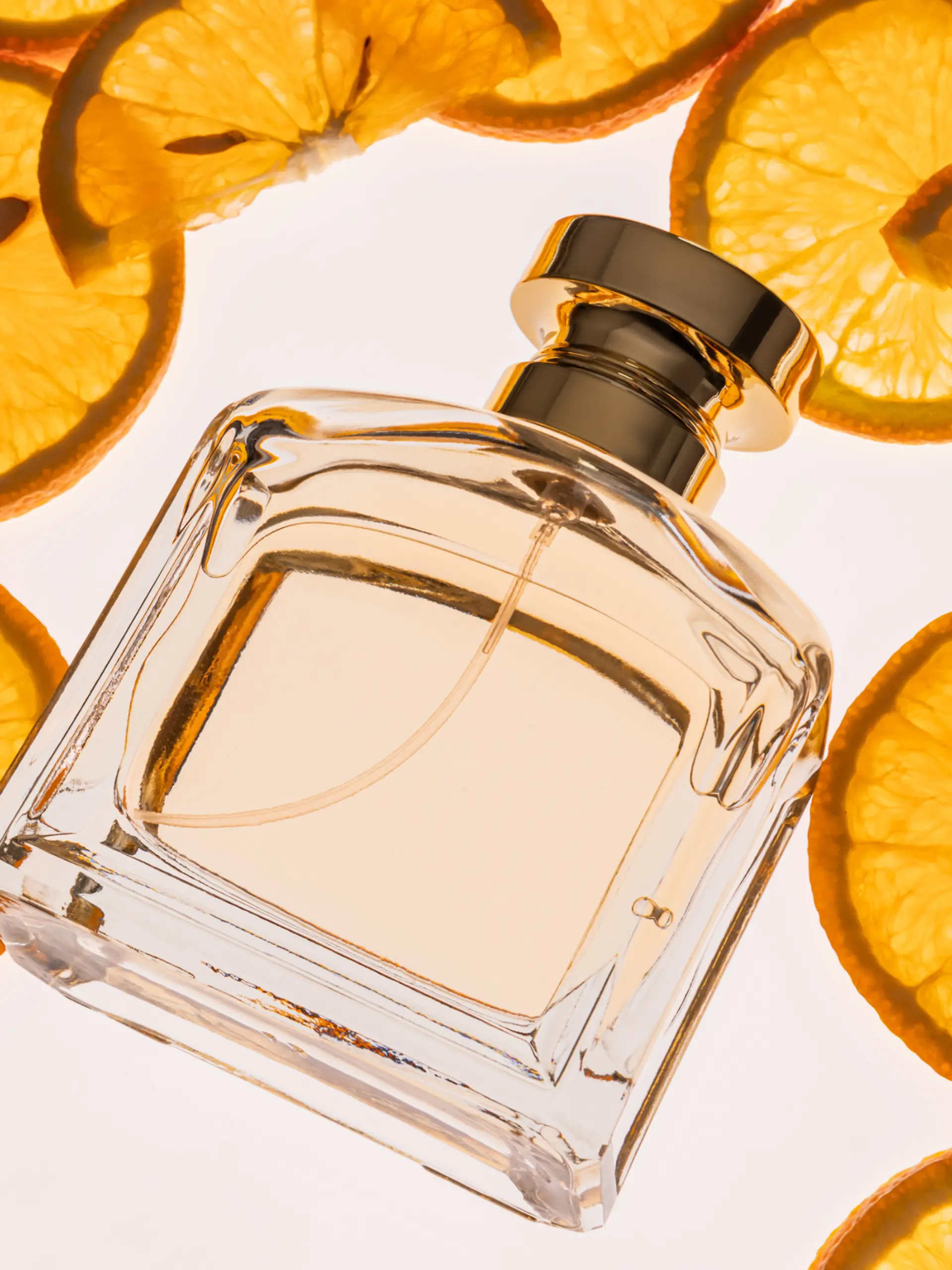 Eine Parfumflasche liegt neben Zitronenscheiben.