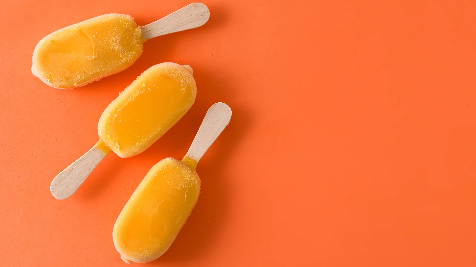 Orangefarbenes Eis am Stiel auf orangenem Hintergrund, das an Solero-Eis erinnert