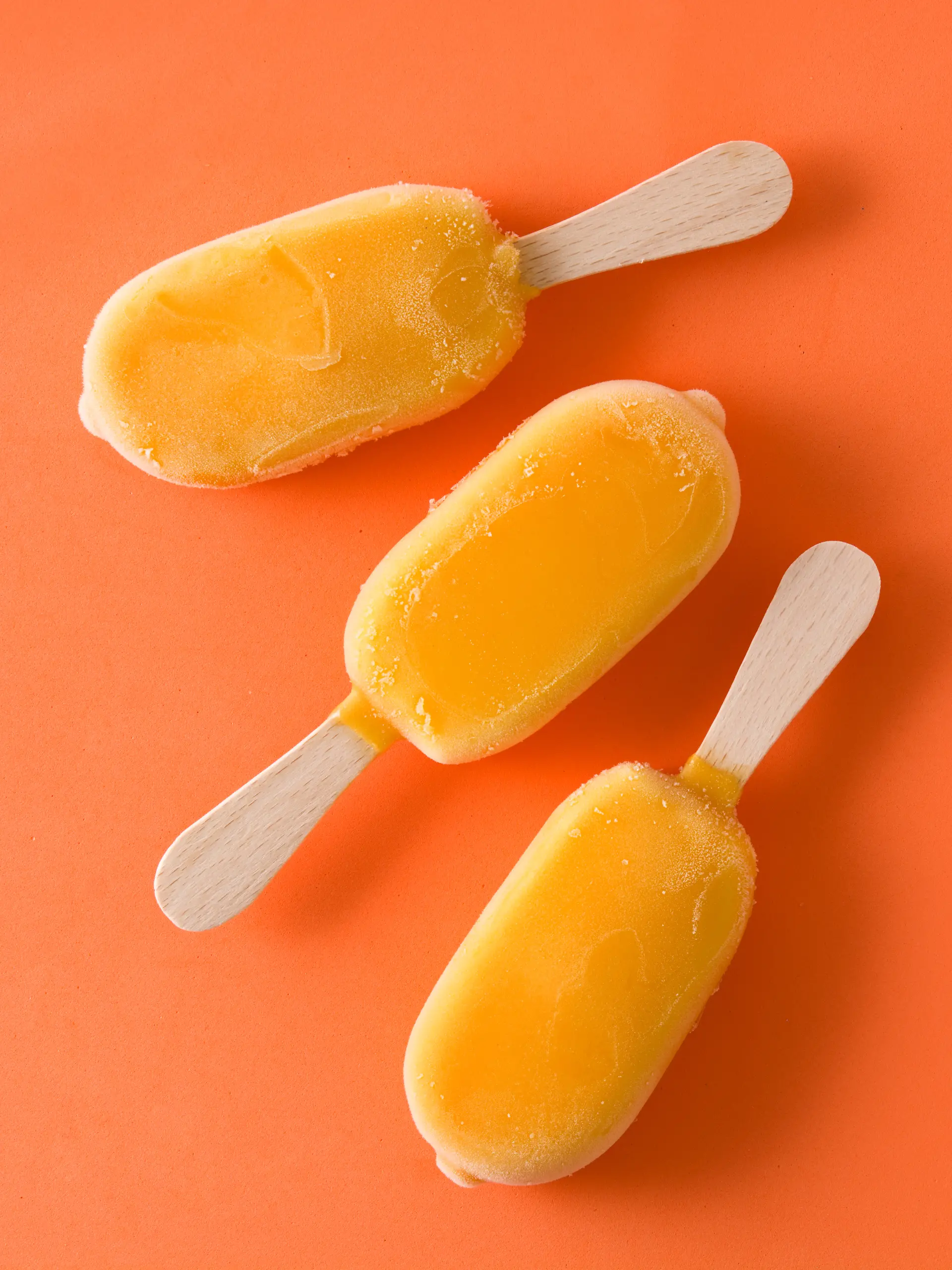 Orangefarbenes Eis am Stiel auf orangenem Hintergrund, das an Solero-Eis erinnert