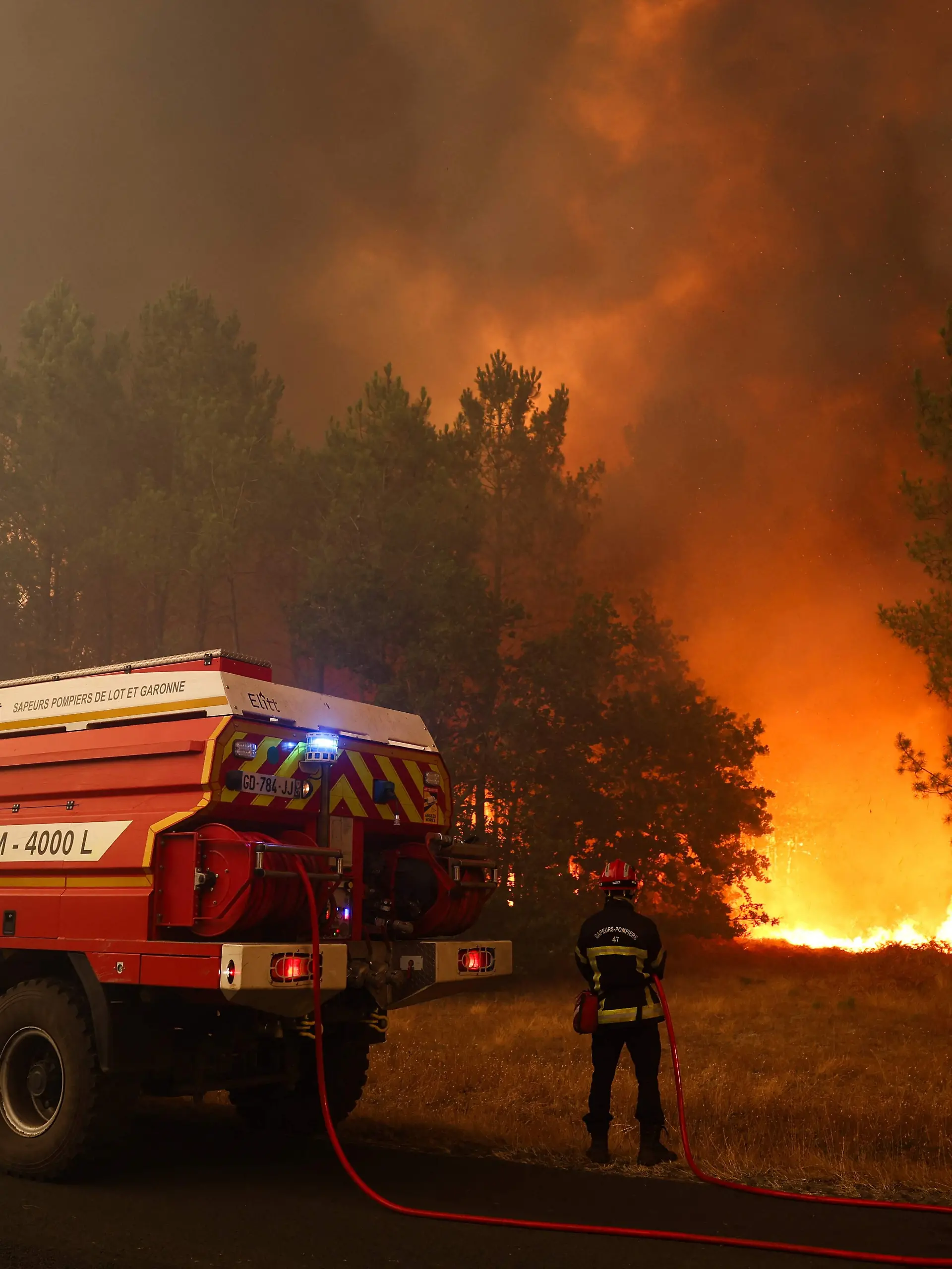 Feuerwehrleute versuchen in der Nähe von Le Porge im Südwesten Frankreichs mit einem Waldbrandlöschfahrzeug, die brennenden Bäume zu löschen. +++ dpa-Bildfunk +++
