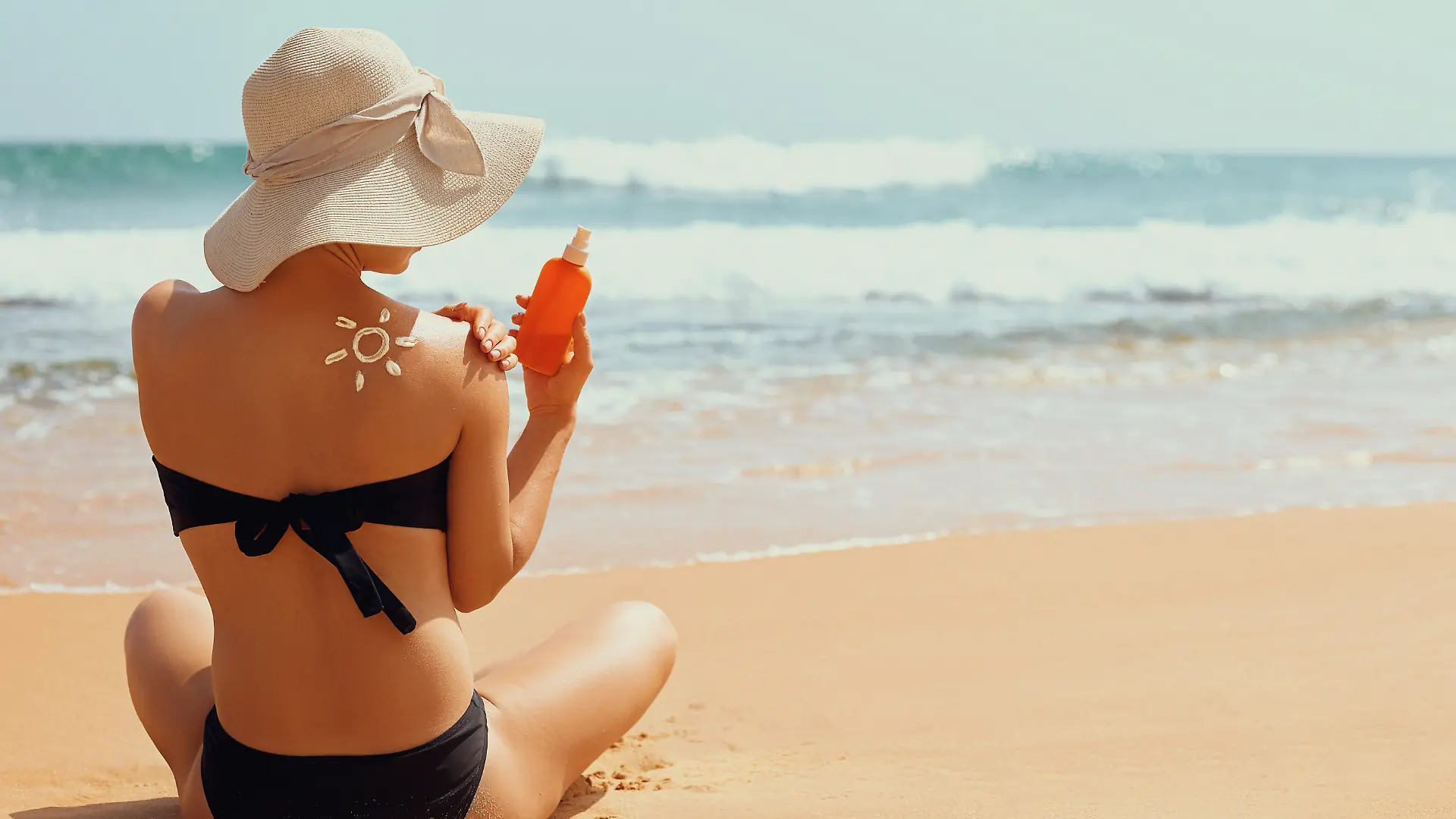 Sun cream on tanned shoulder with sun shape . Sun protection. Beautiful woman in bikini applying  Solar Cream. Skin and body care.Portrait of female holding suntan lotion and moisturizing sunblock.