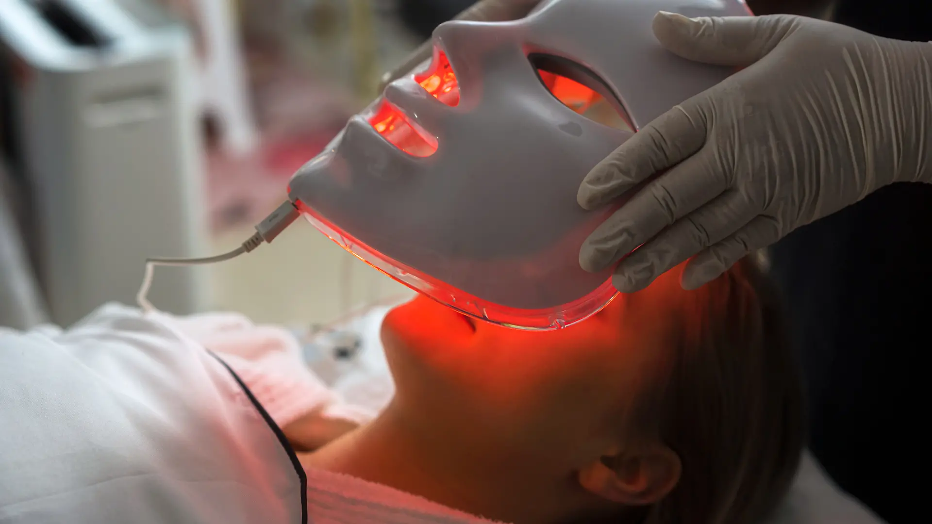 Frau wird LED-Maske aufgesetzt