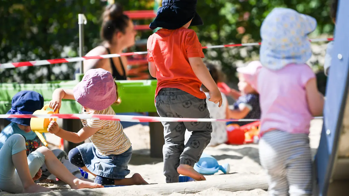 ARCHIV - 02.06.2020, Offenbach/Main: Kinder einer Krippen-Gruppe spielen auf dem Spielplatz der Kita, auf dem Absperrbänder den Abstand zu den Gruppen markieren. (zu dpa «Im Saarland dürfen wieder mehr Kinder in die Kitas») Foto: Arne Dedert/dpa +++ dpa-Bildfunk +++