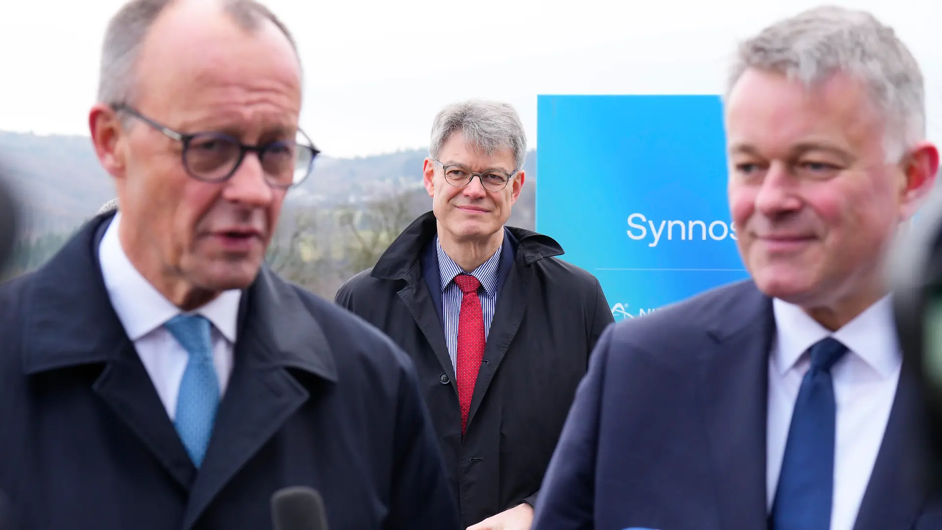 Verkehrsminister Patrick Schnieder im Hintergrund beobachtet er das Pressestatement von seinem Bruder CDU Spitzenkandidat Gordon Schnieder mit Bundeskanzler Friedrich Merz im Rahmen der der Eroeffnung des Niedax Technologie Campus,. Im Hintergrund Verkehrsminister Patrick Schnieder;Neustadt/Wied, 02.02.2026