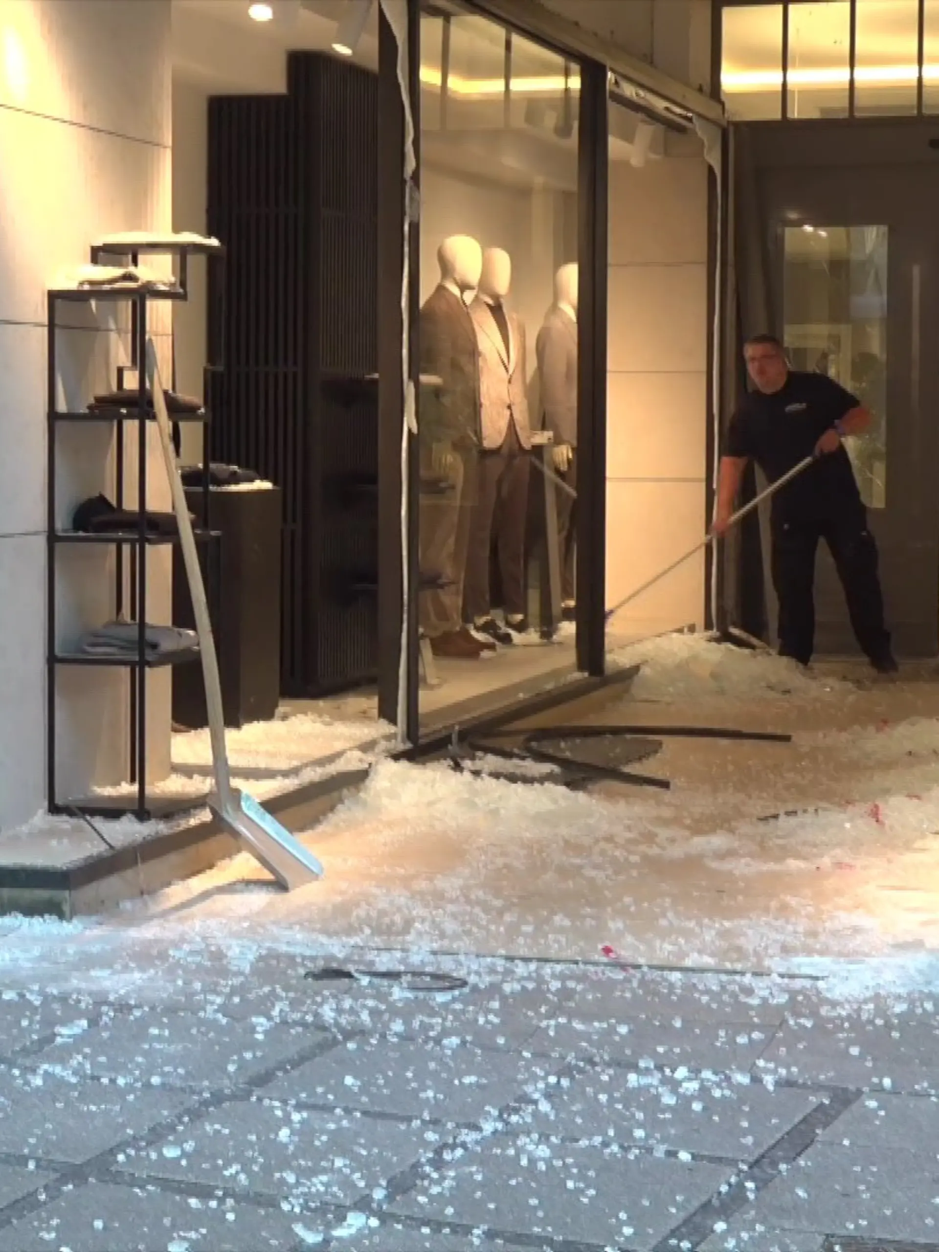 Nach der Explosion fegt ein Mitarbeiter die Glasscherben vor dem beschädigten Schaufenster zusammen. 
