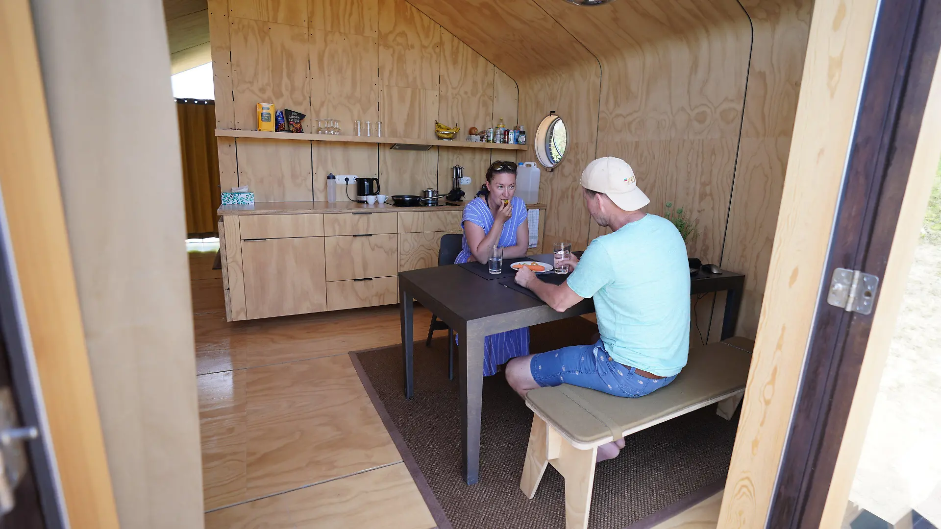 16.06.2021, Schleswig-Holstein, Helgoland: Monique Eichhorn und Sebastian Ebeling, Urlauber aus Berlin, sitzen in einem sogenannten Wikkelhouse auf der Helgoländer Düne. Die beiden sogenannten Wikkelhouses aus einer Manufaktur in Amsterdam sind nach Angaben des Helgoland Tourismus-Services für diese Saison ausgebucht. Auch im kommenden Jahr sind die Tiny Houses, die nur online und wochenweise gebucht werden können, bereits belegt. Die kleinen Häuser, deren Wände im Kern aus 24 miteinander verwickelter Schichten Pappe bestehen, sind komplett ausgestattet - es gibt aber kein Wasser und keine Toilette. (zu dpa «Gefragte Pappe: Helgoland möchte mehr Wikkelhouses») Foto: Marcus Brandt/dpa +++ dpa-Bildfunk +++